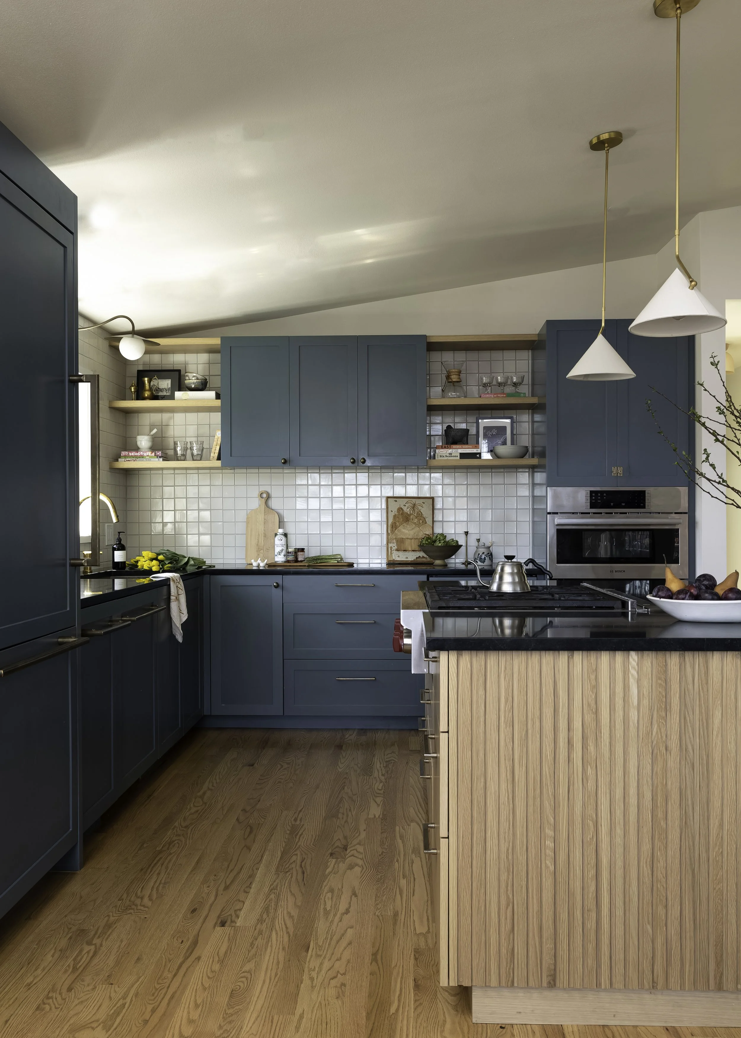 Modern kitchen with blue cabinets, white tiled backsplash, a wooden island, and open shelves with kitchenware and decor.