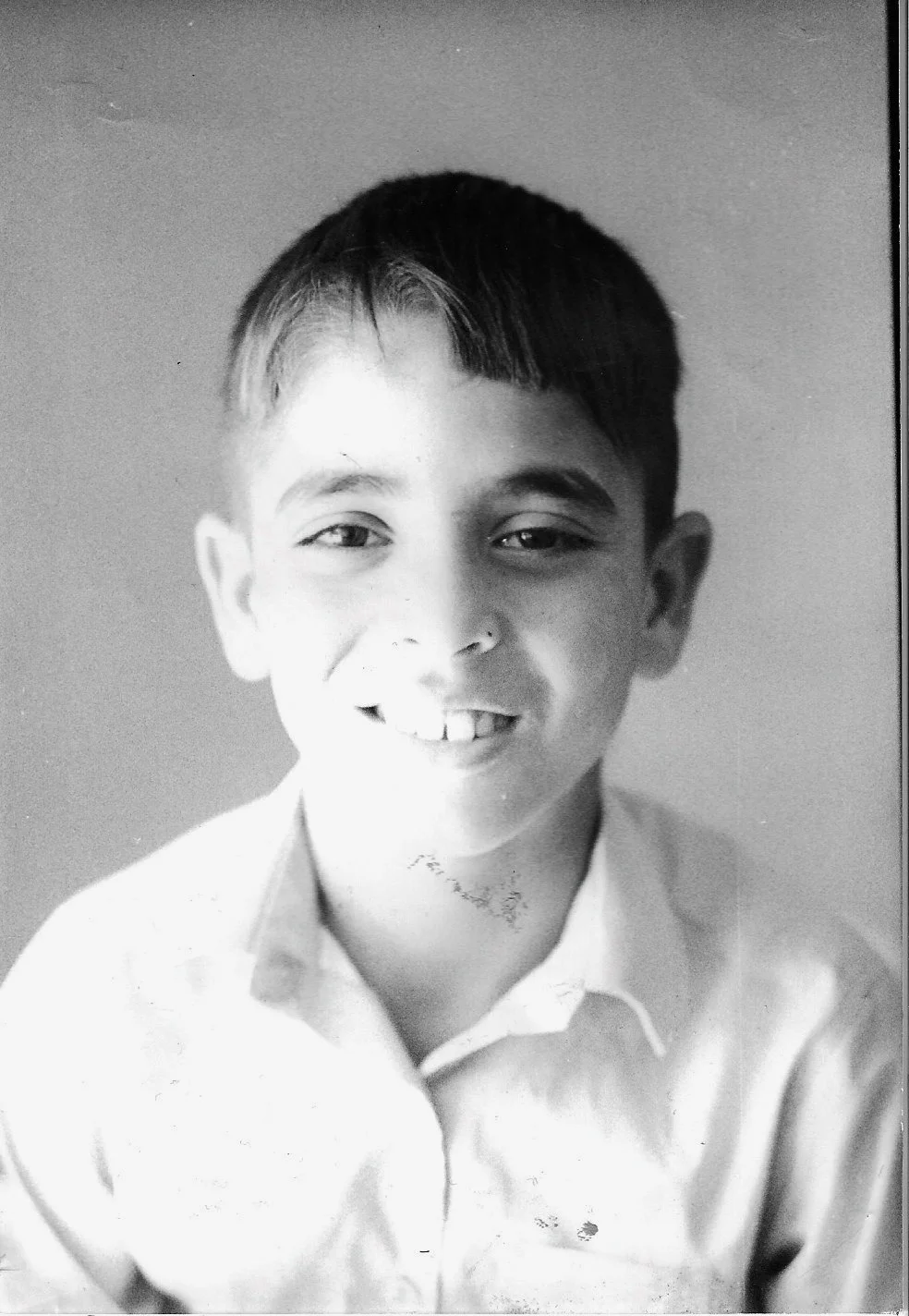 Black and white portrait of a smiling young boy in a collared shirt.