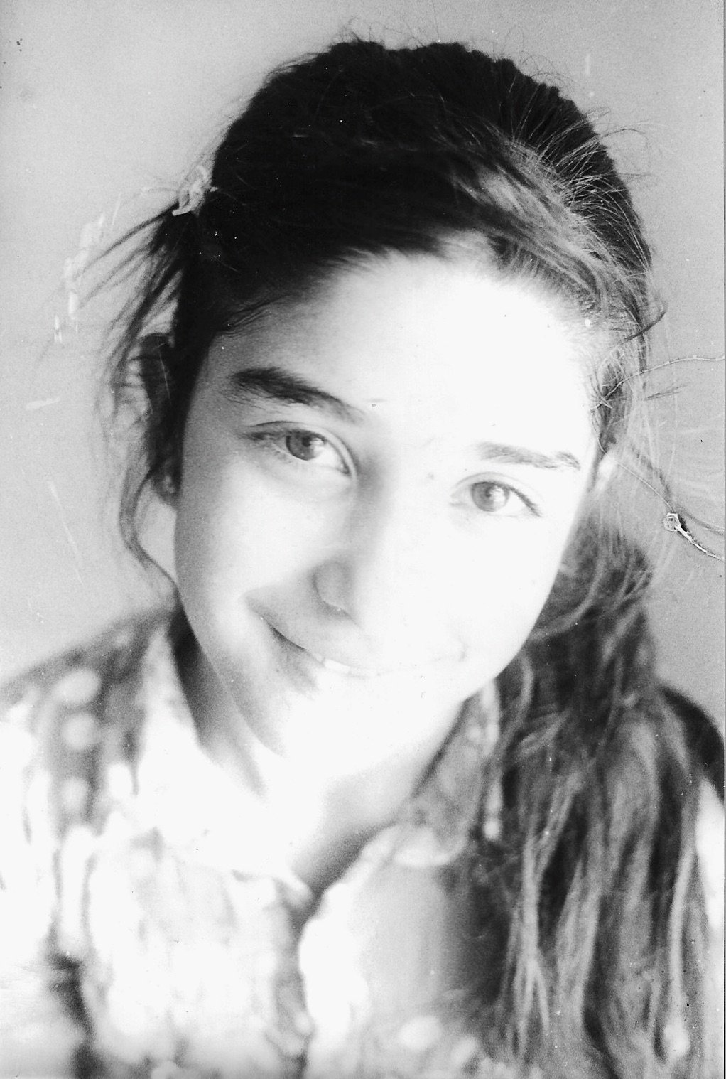 Black and white portrait of a young woman with long, wavy hair, smiling gently and looking at the camera.