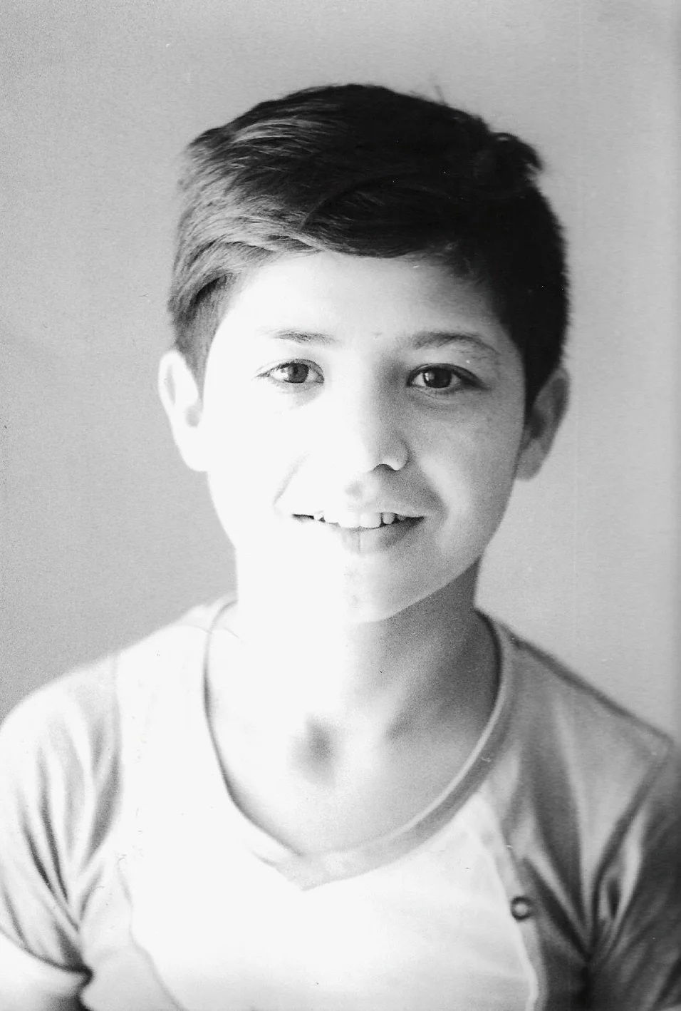 Black and white portrait of a young boy with short, styled hair, smiling slightly, wearing a T-shirt.