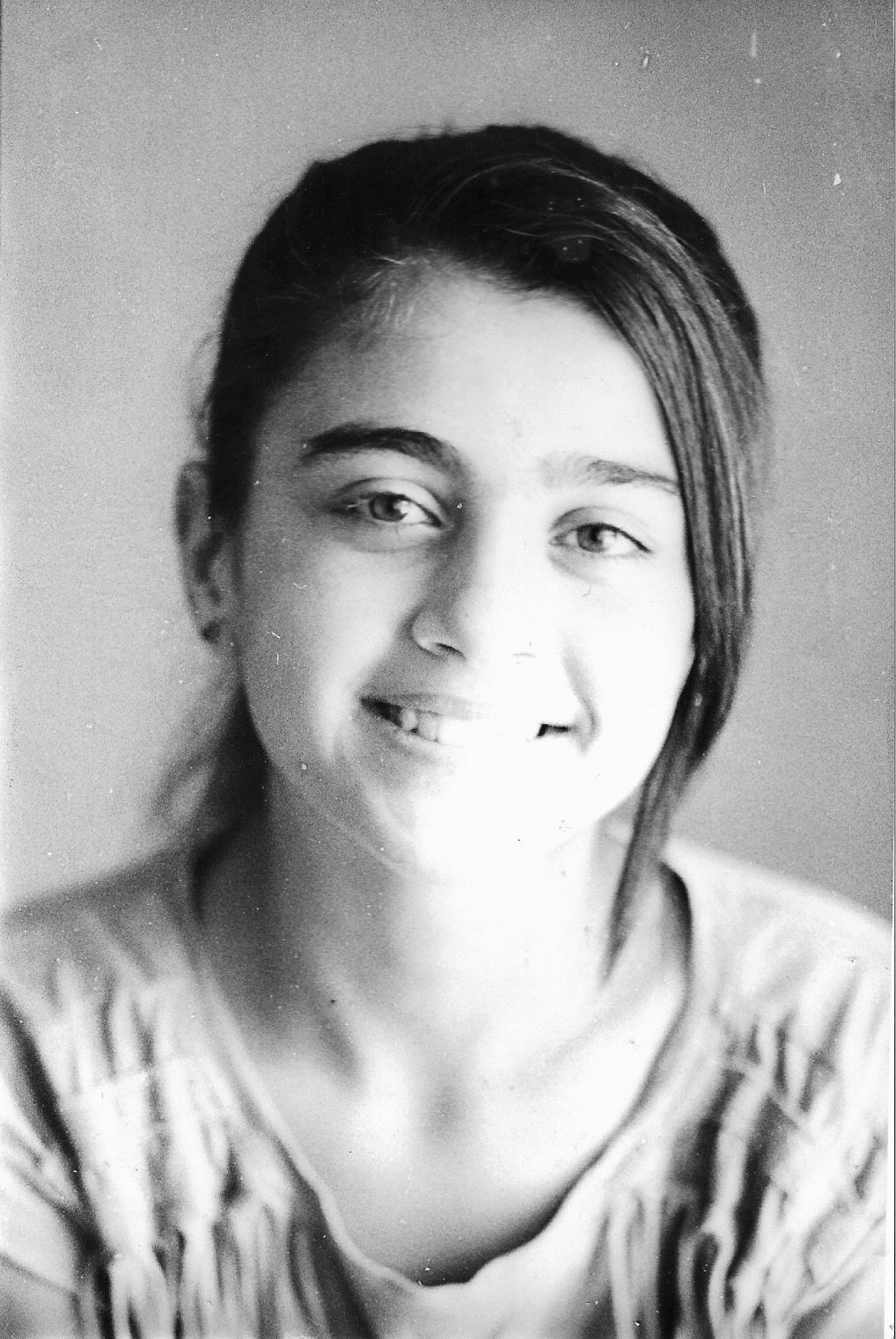 A black-and-white portrait of a young woman with short, styled hair, smiling slightly, wearing a striped shirt.