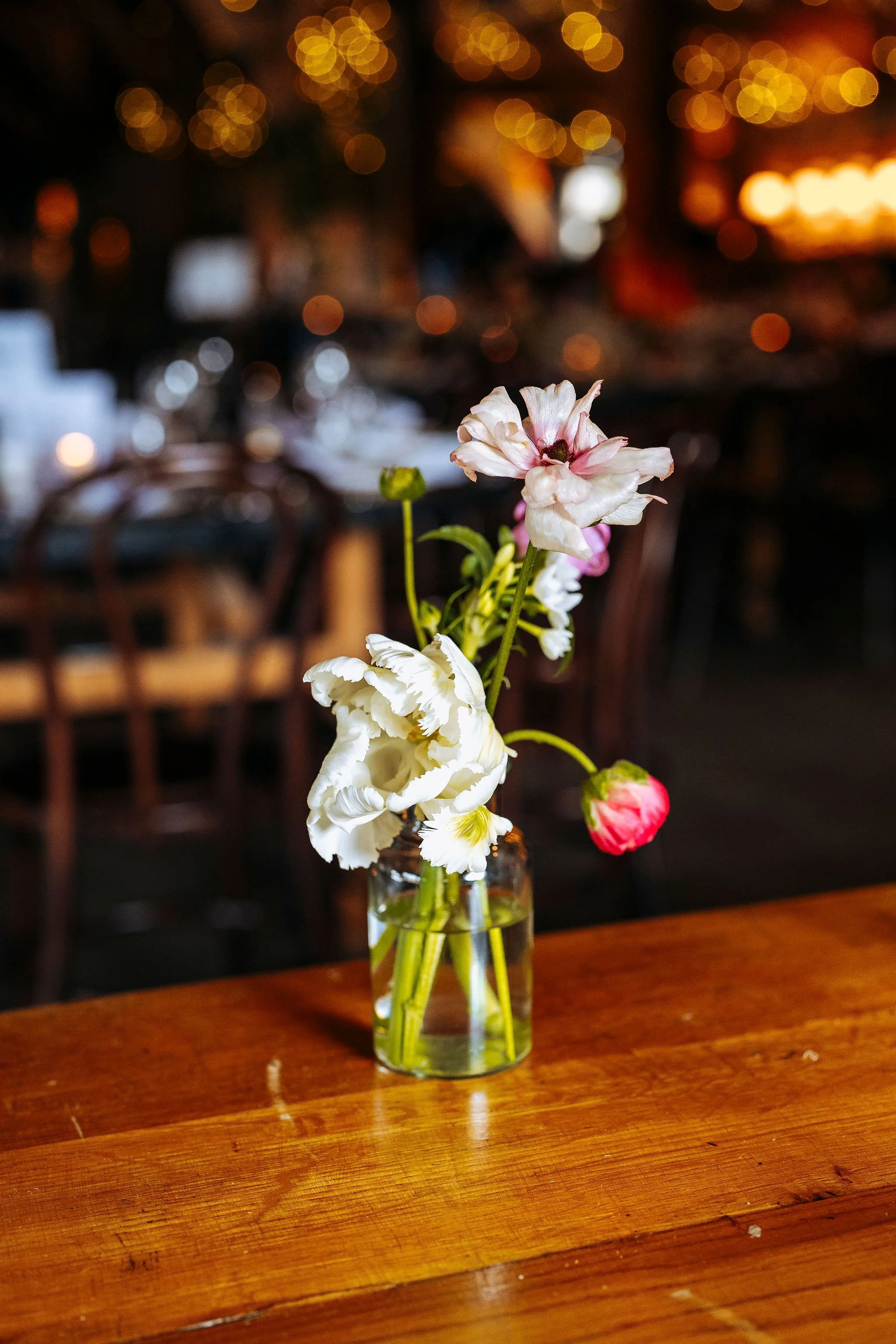 bud vase on guest table at wedding with tulips and butterfly ranunculus at The Tithe Barn, Bolton Abbey