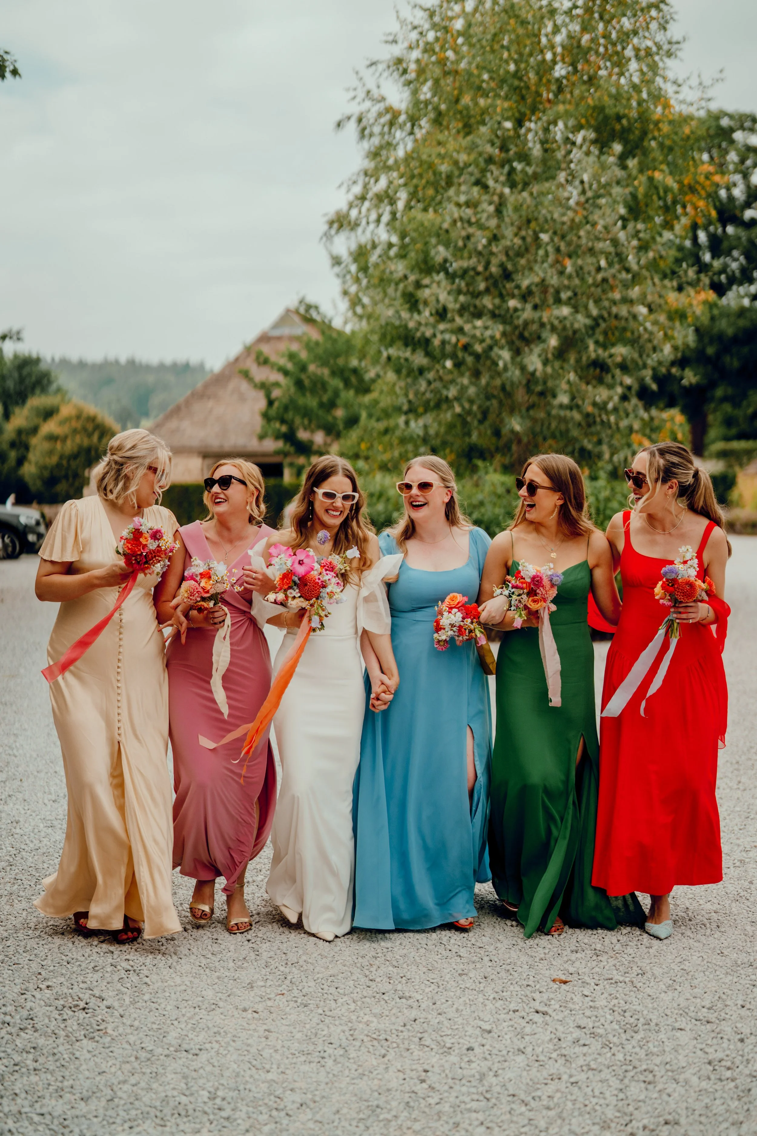 bride with her colourful bridesmaids in brightly coloured dresses, holding vibrant floral bouquets at the Tithe Barn, Bolton Abbey, Yorkshire