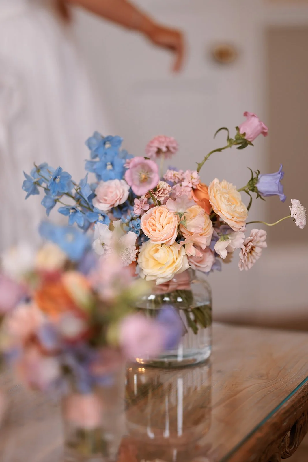 Butter yellow, sky blue, pastel pink, lilac and pale coral summer bridal bouquet in a vase on a coffee table at Middleton Lodge, North Yorkshire