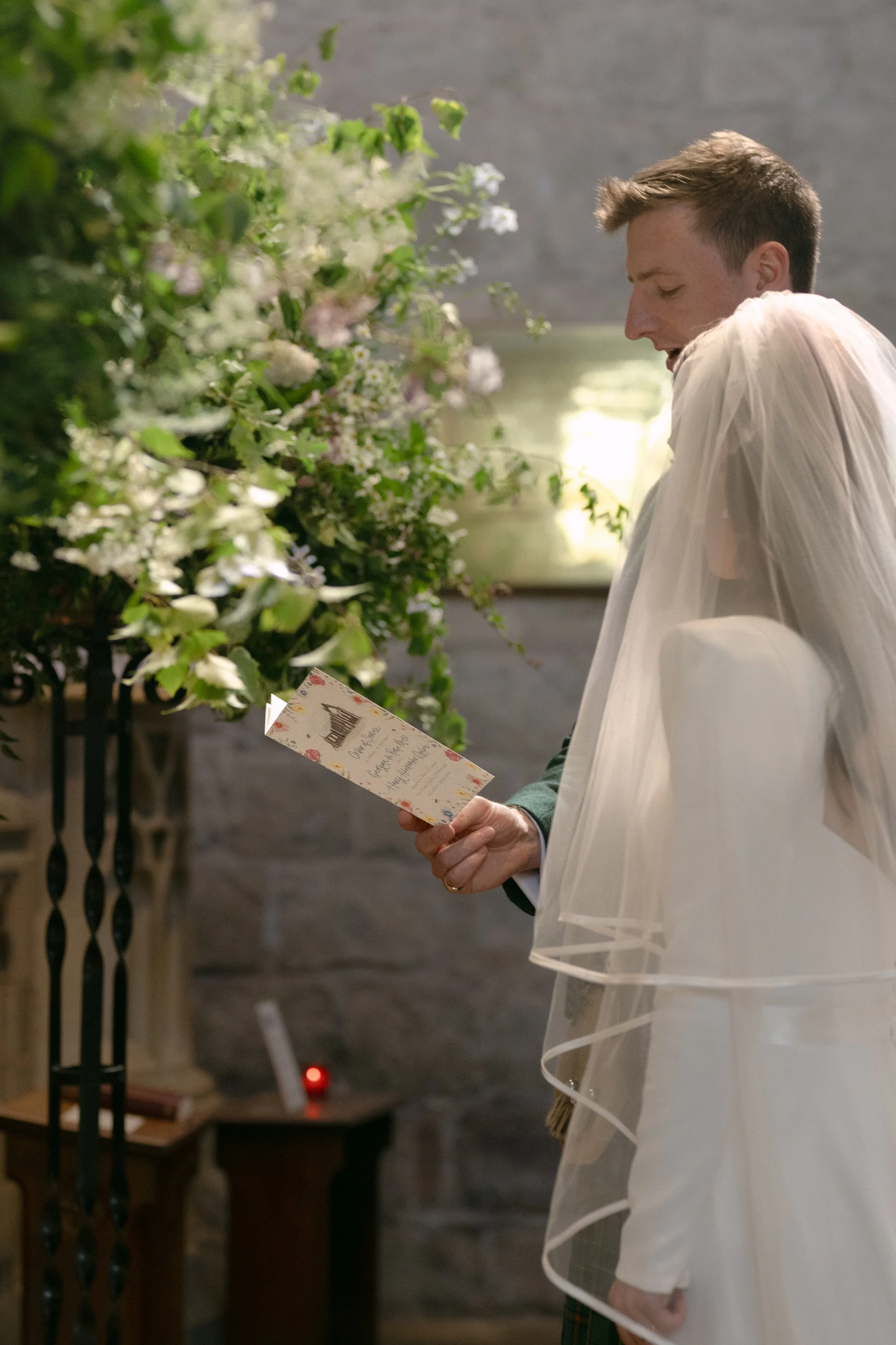 Couple getting married in Bolton Priory Church, Bolton Abbey, Yorkshire. Church flowers in greens, whites and pinks 