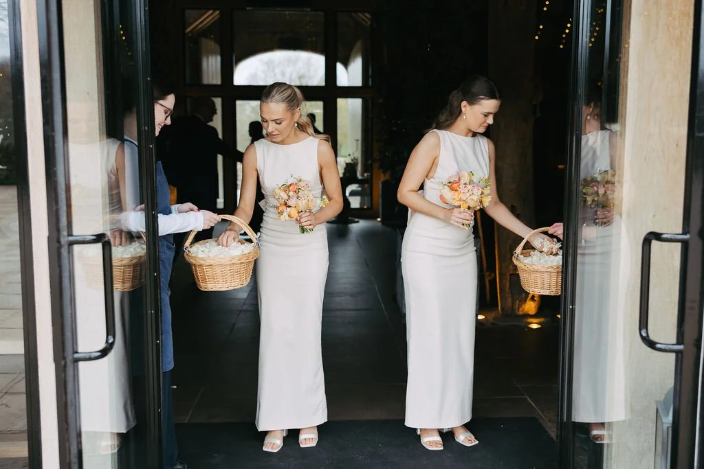 two bridesmaids holding their spring bouquets and getting a handful of fresh rose petal confetti at The Tithe Barn, Bolton Abbey, Yorkshire