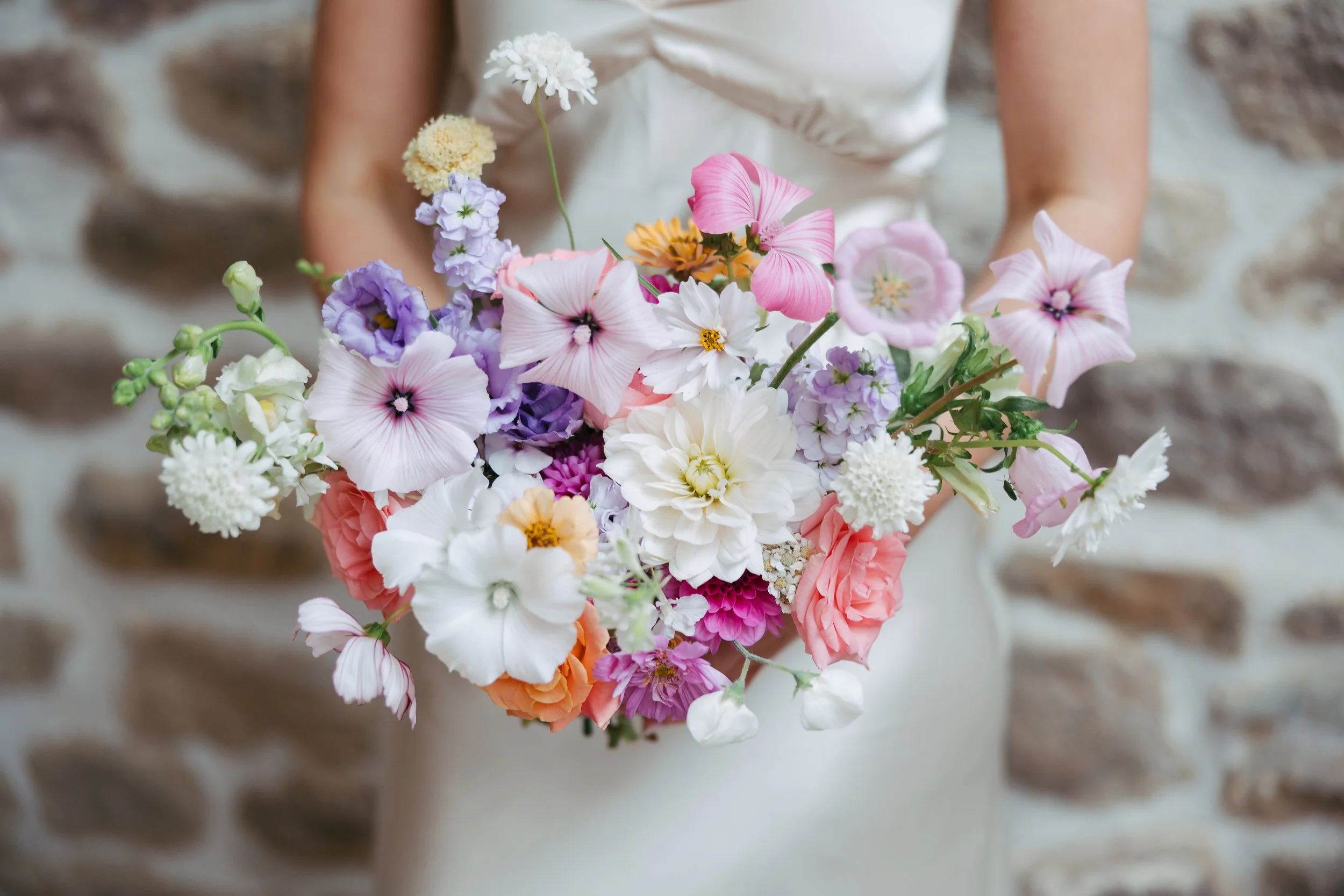 Beautiful July bridal bouquet with lilacs, pinks, whites, and coral. British grown flowers.