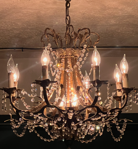 Elegant crystal chandelier with lit candle-shaped bulbs hanging from a chain.