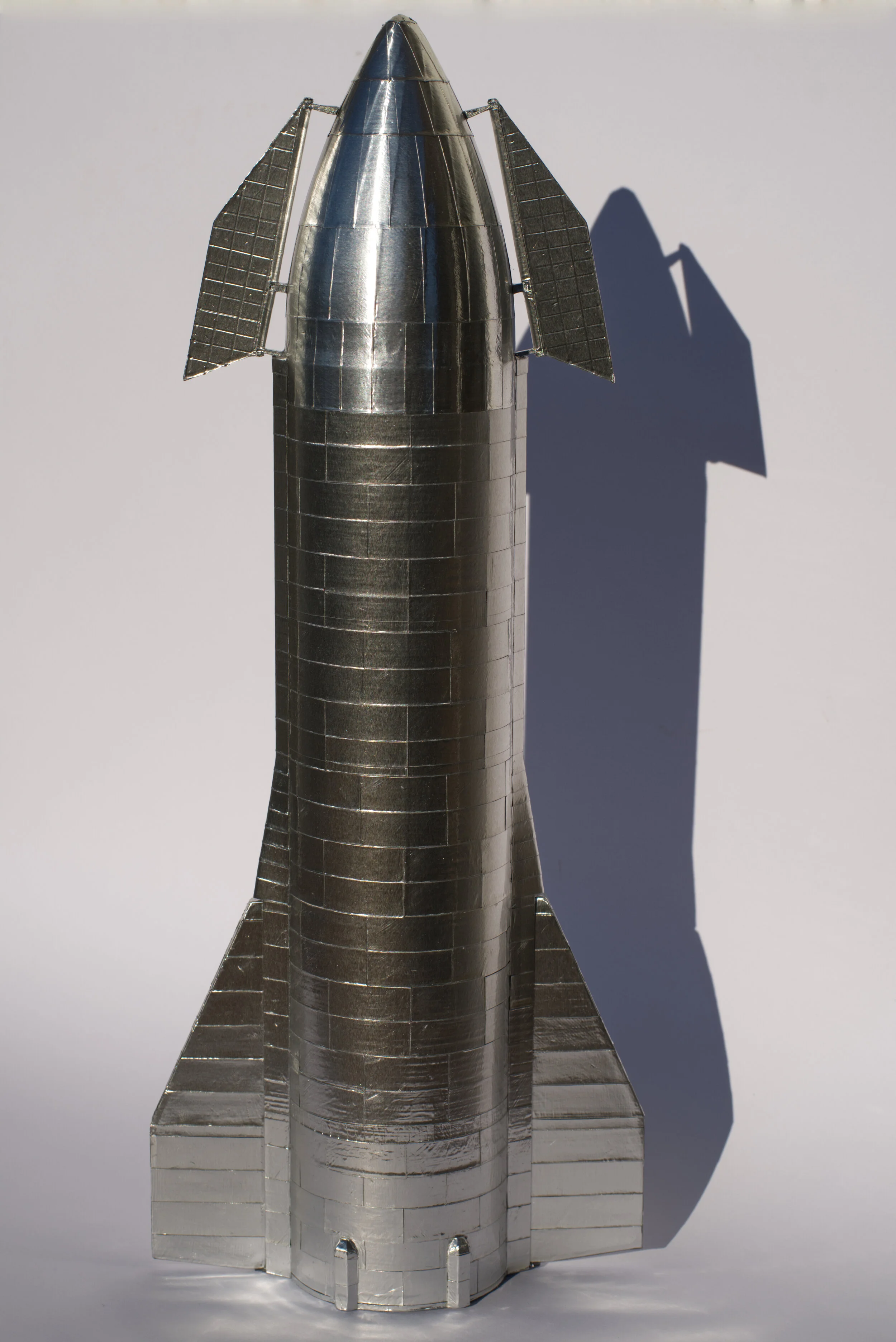  The engines, upper flap hinges and engine bay were airbrushed. After assembling the fuselage, it and the flaps were plated with panels cut from aluminum tape to mimic the stainless steel panels of the original Starship Mk1.  The flaps were then glue