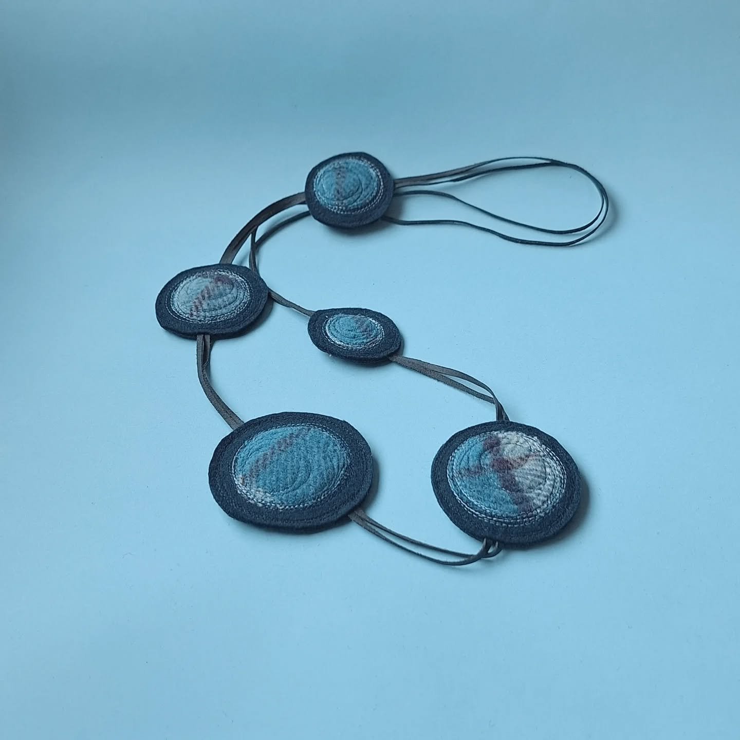 This Shinzo necklace began as fragments.

Repurposed upholstery felt, vintage wool blanket offcuts shared by a fellow maker, leather chosen for its durability.

Materials move from one life to another&mdash;kept in circulation, worked by hand, given 