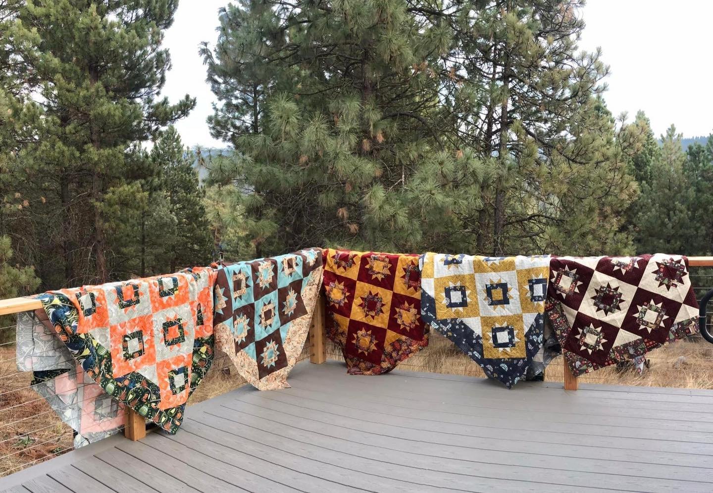 Quilters showing their completed projects off of the back deck