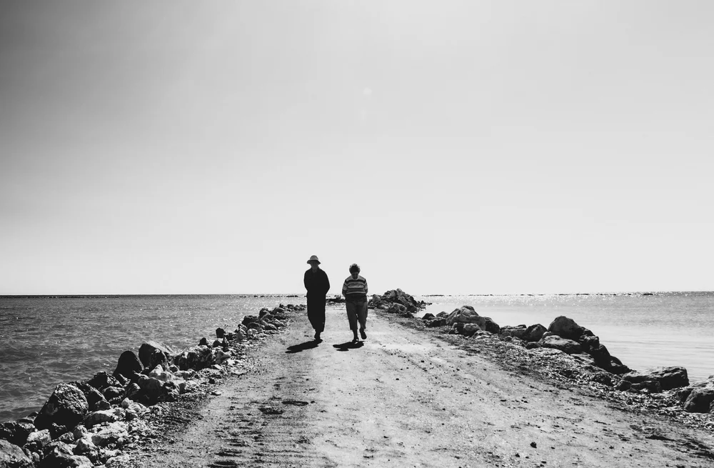 To the End (Together): an older couple walking side by side along a stone pier, Cyprus, in black and white