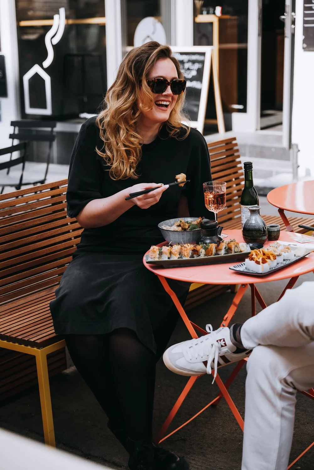 Guests laughing over sushi on a café terrace