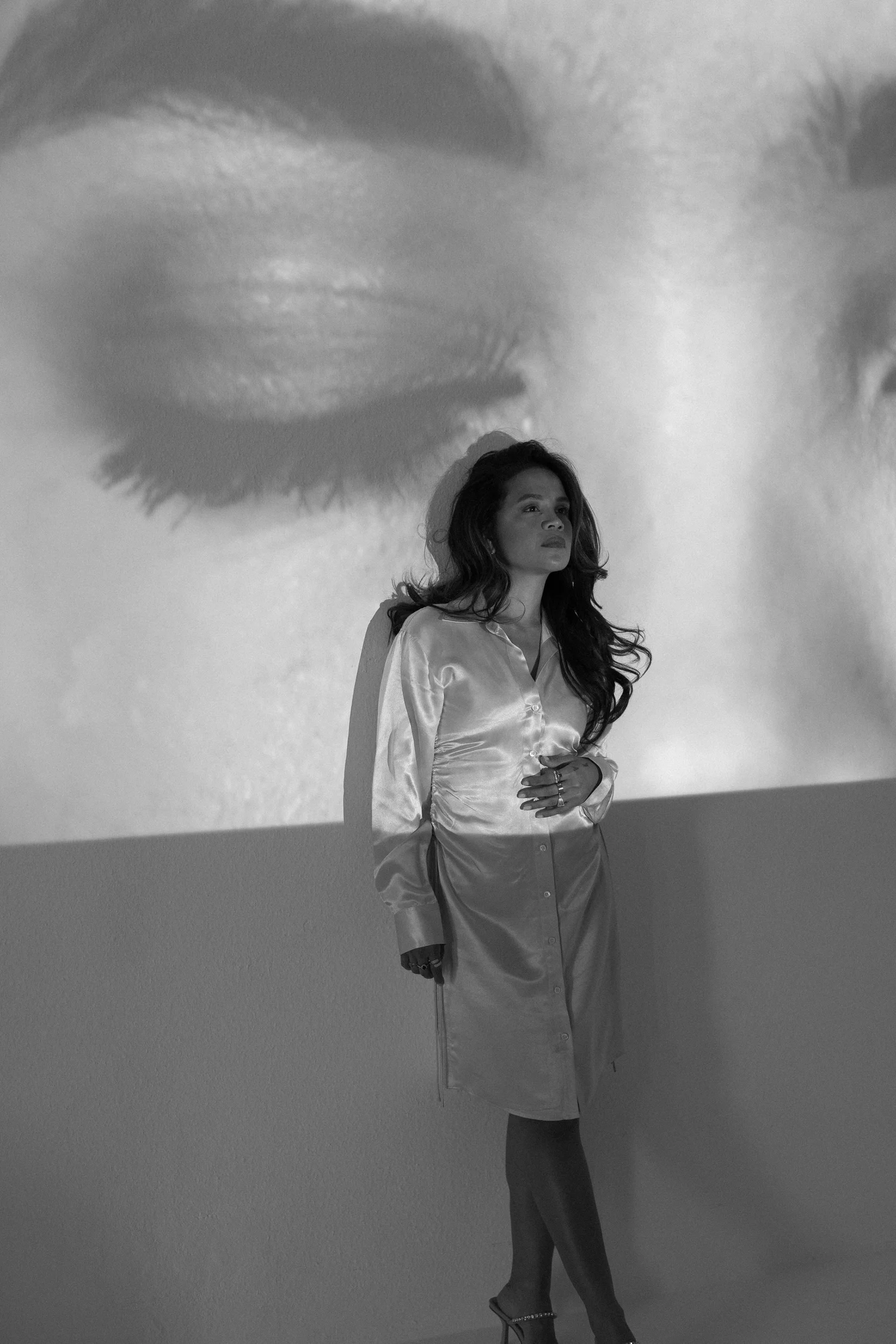 Wynn Florante in black and white, standing in front of a projection of a closed eye