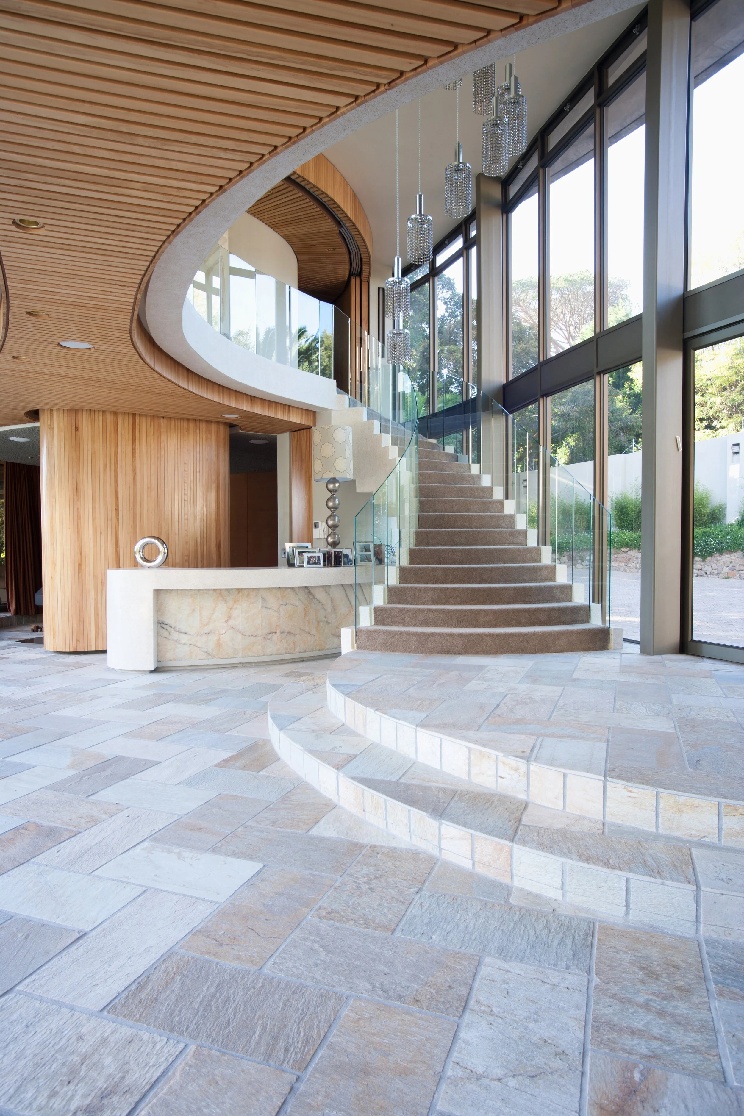 Modern interior with a stairway, large glass windows, wood accents, and hanging pendant lights.