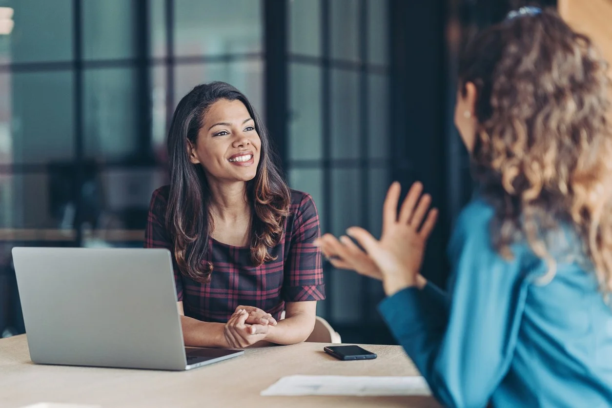 A woman interviews a potential employee at a desk in an office