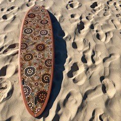 Indigenous art on a surfboard on the beach