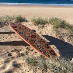 Indigenous art on a surfboard on the beach