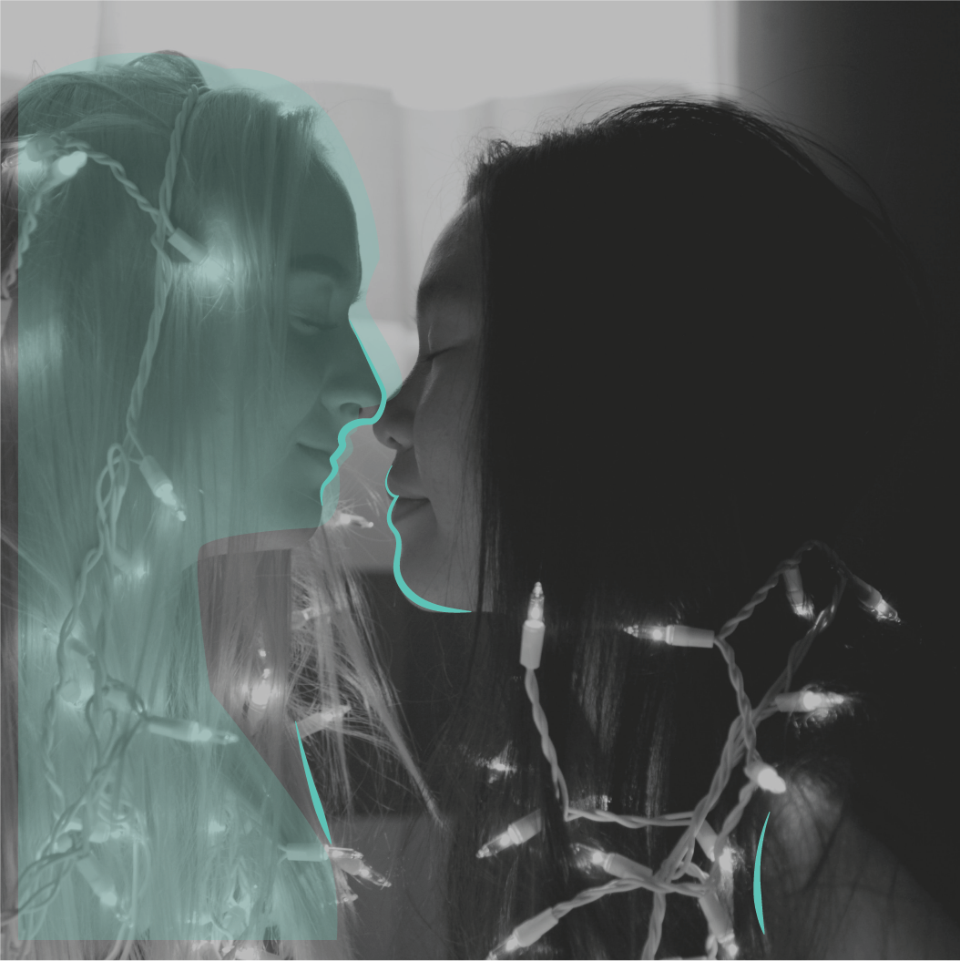 Same sex couple kissing surrounded by fairy lights