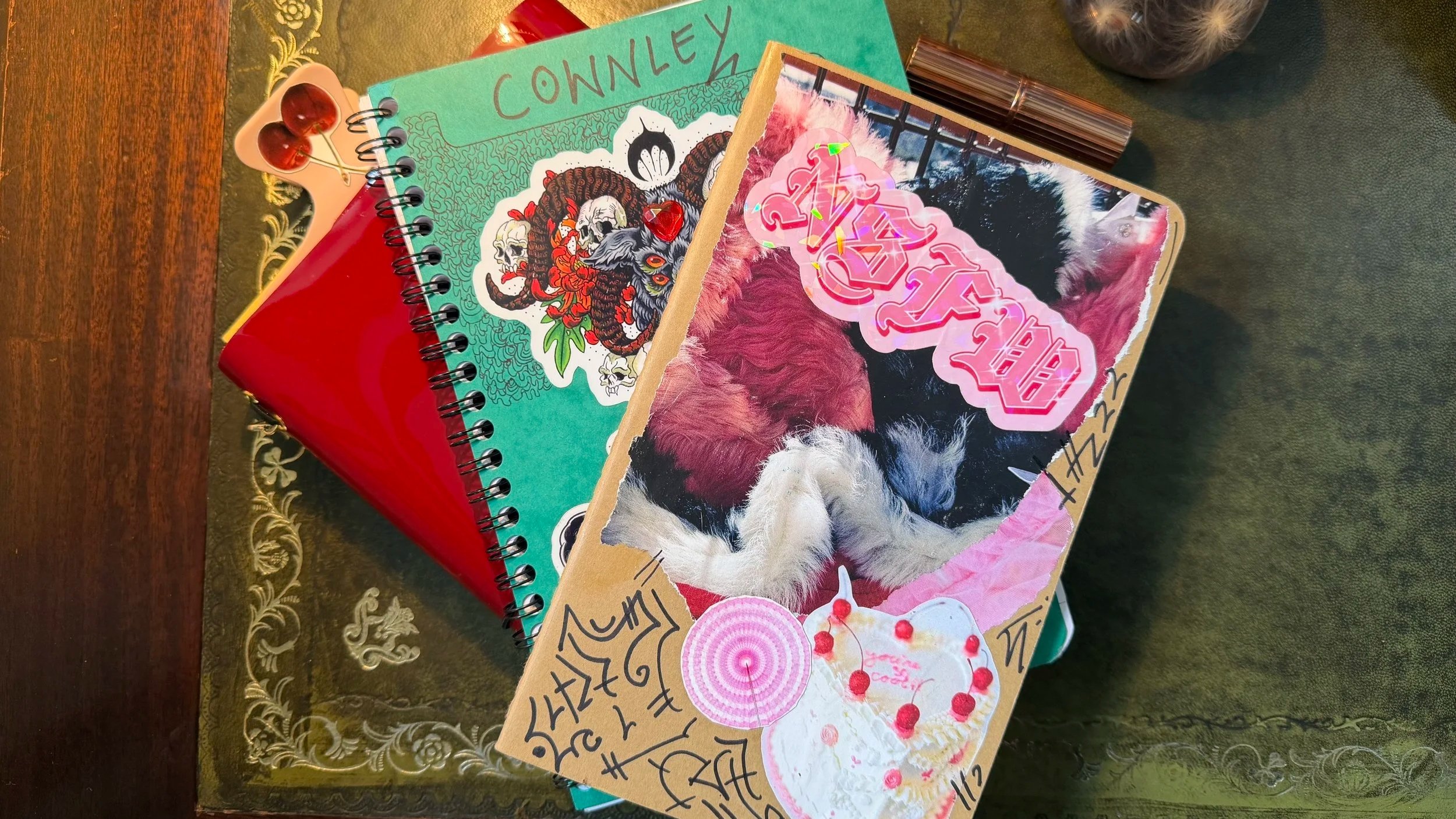 Top down view od my notebooks and planners on my leather-topped desk. Each notebook has been customised with stickers and doodles.