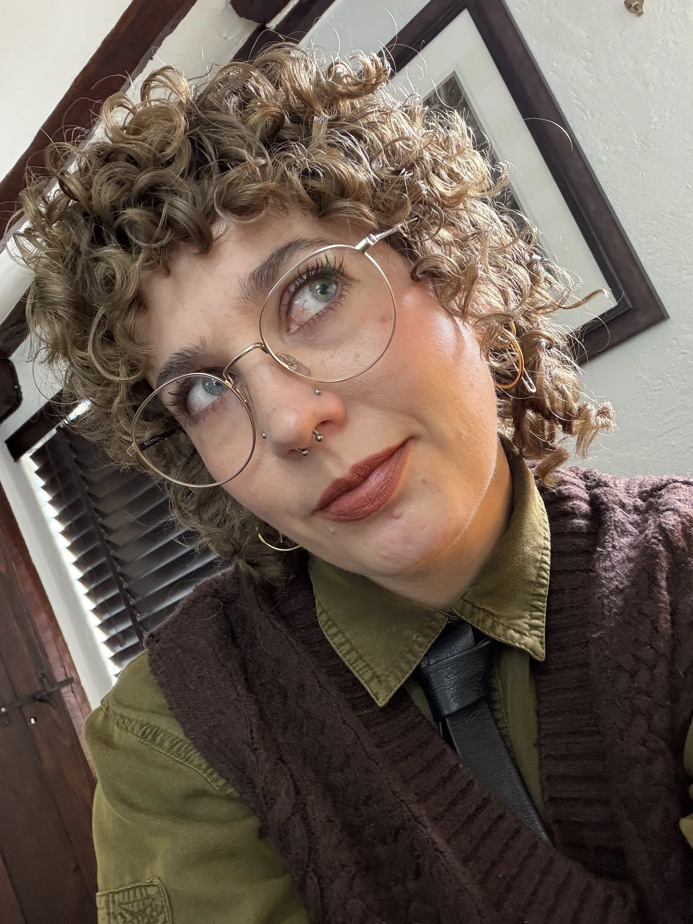 Me, Emma Cownley, smiling into the camera. I have blue eyes, curly light-brown hair, and I'm a white Millennial woman (sorry).