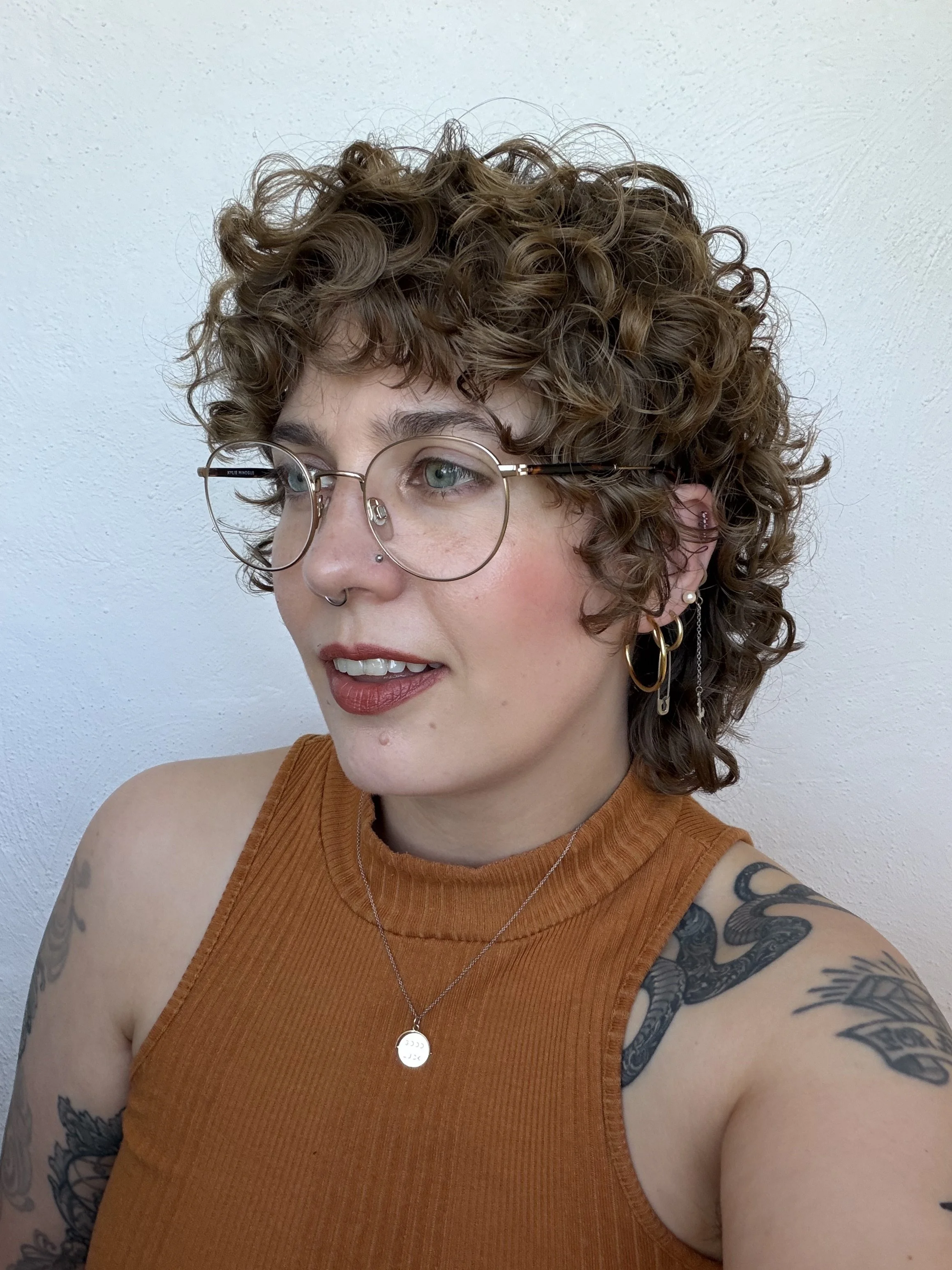 side profile photo of me, a white Millennial woman with light brown hair and greeny blue eyes. I'm wearing a marigold top and a pair of glasses.