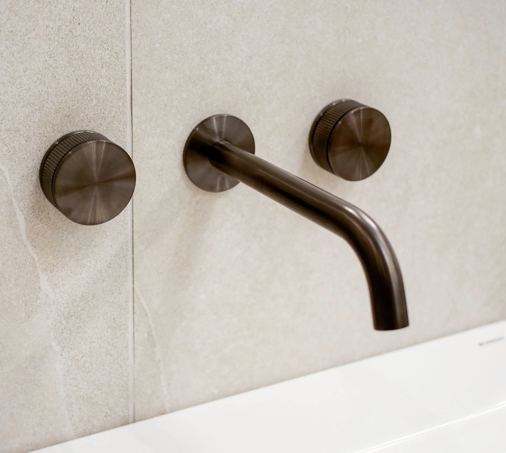 Close-up of a wall-mounted indoor hand sanitizer dispenser with a dark metallic finish.