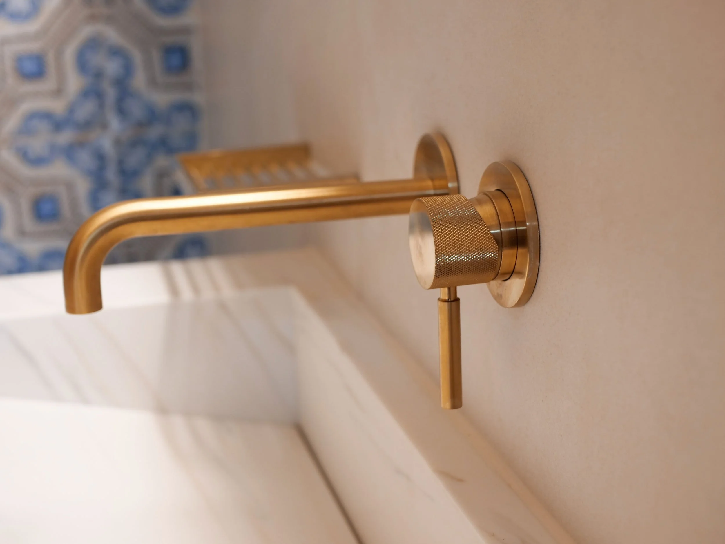 A gold-colored bathroom faucet with a historic design on a beige countertop.