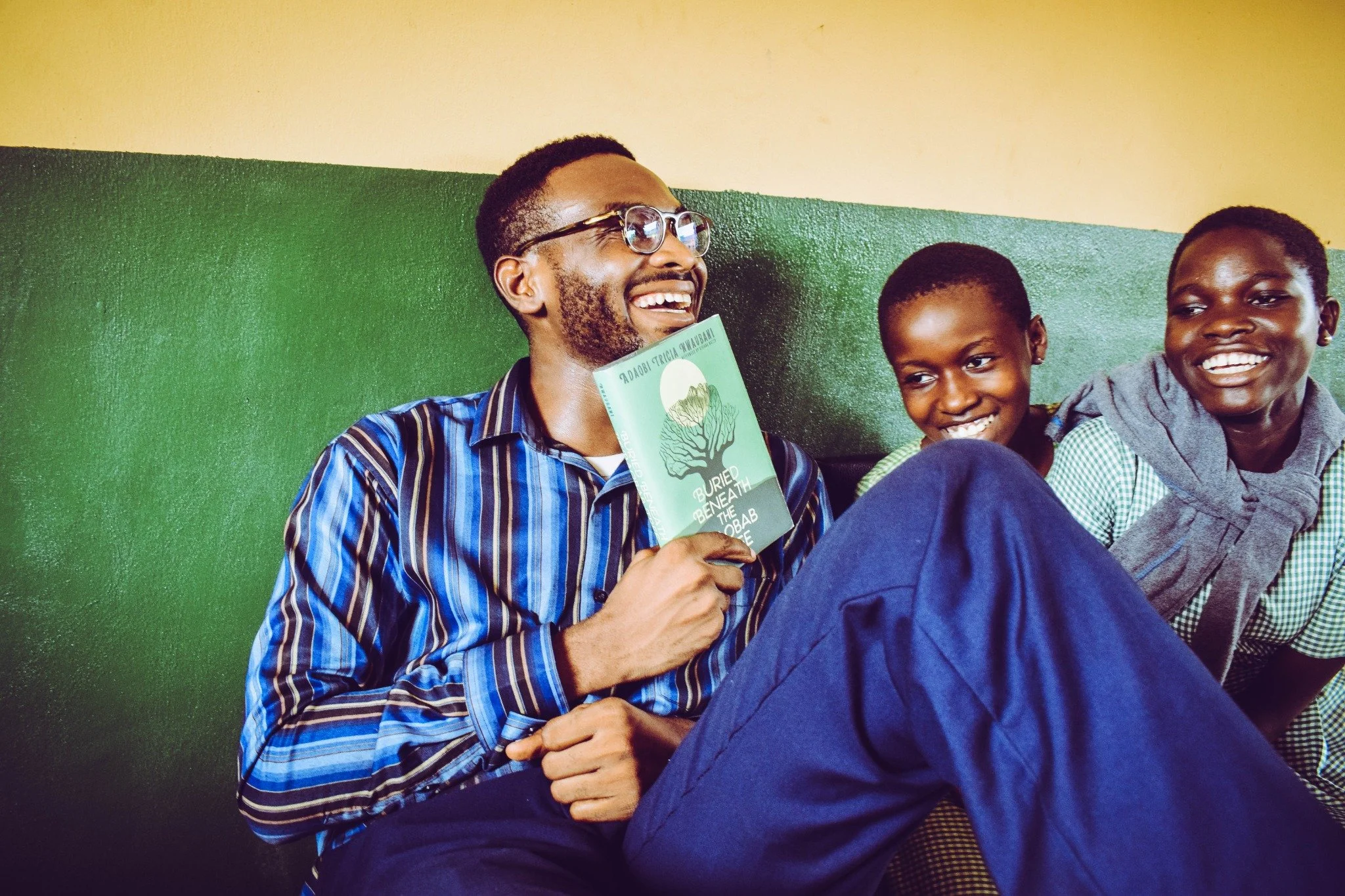 A teacher and pupils sharing a joyful moment with a book in a classroom