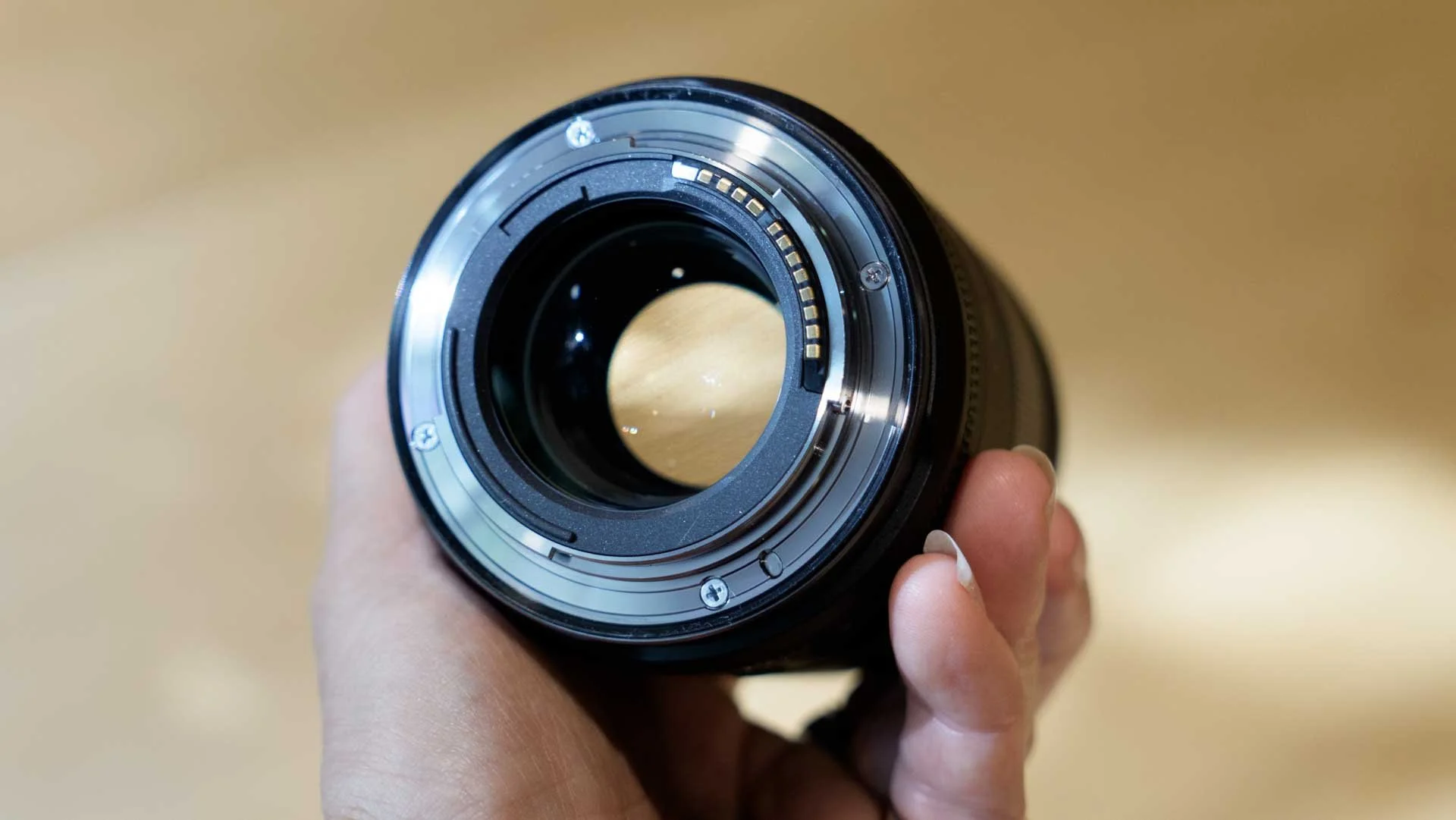 The Canon RF 85mm F1.4L VCM in a woman's hand showing the metal mount