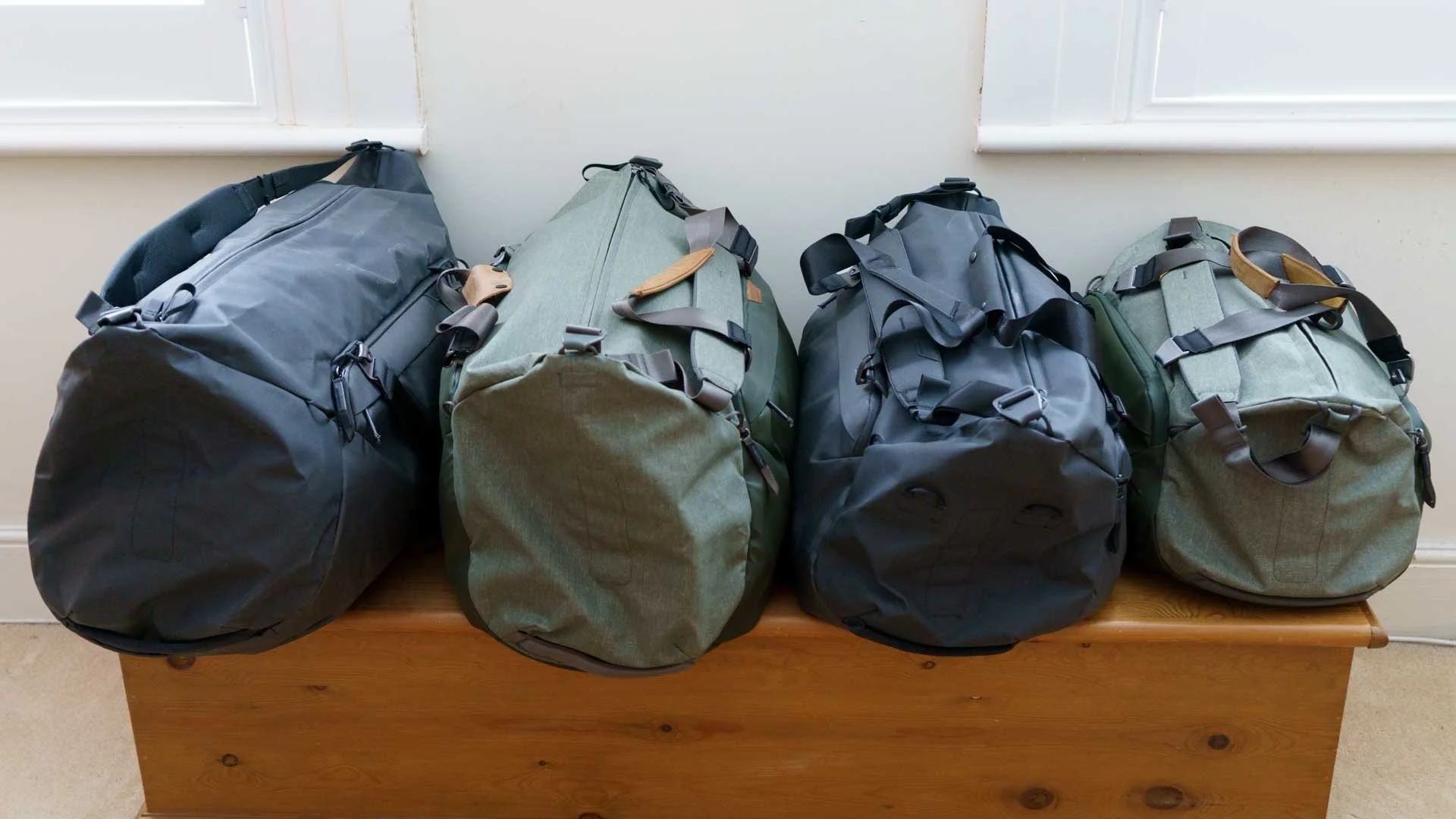 From left to right, the Peak Design Travel Duffel 80L, 65L, 50L and 35L bags, and in Black, Sage, Black and Sage.
