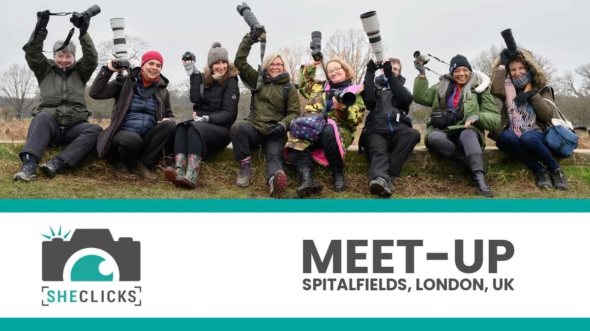 Group of photographers posing with cameras outdoors, with text “SheClicks Meet-Up Spitalfields, London, UK.”