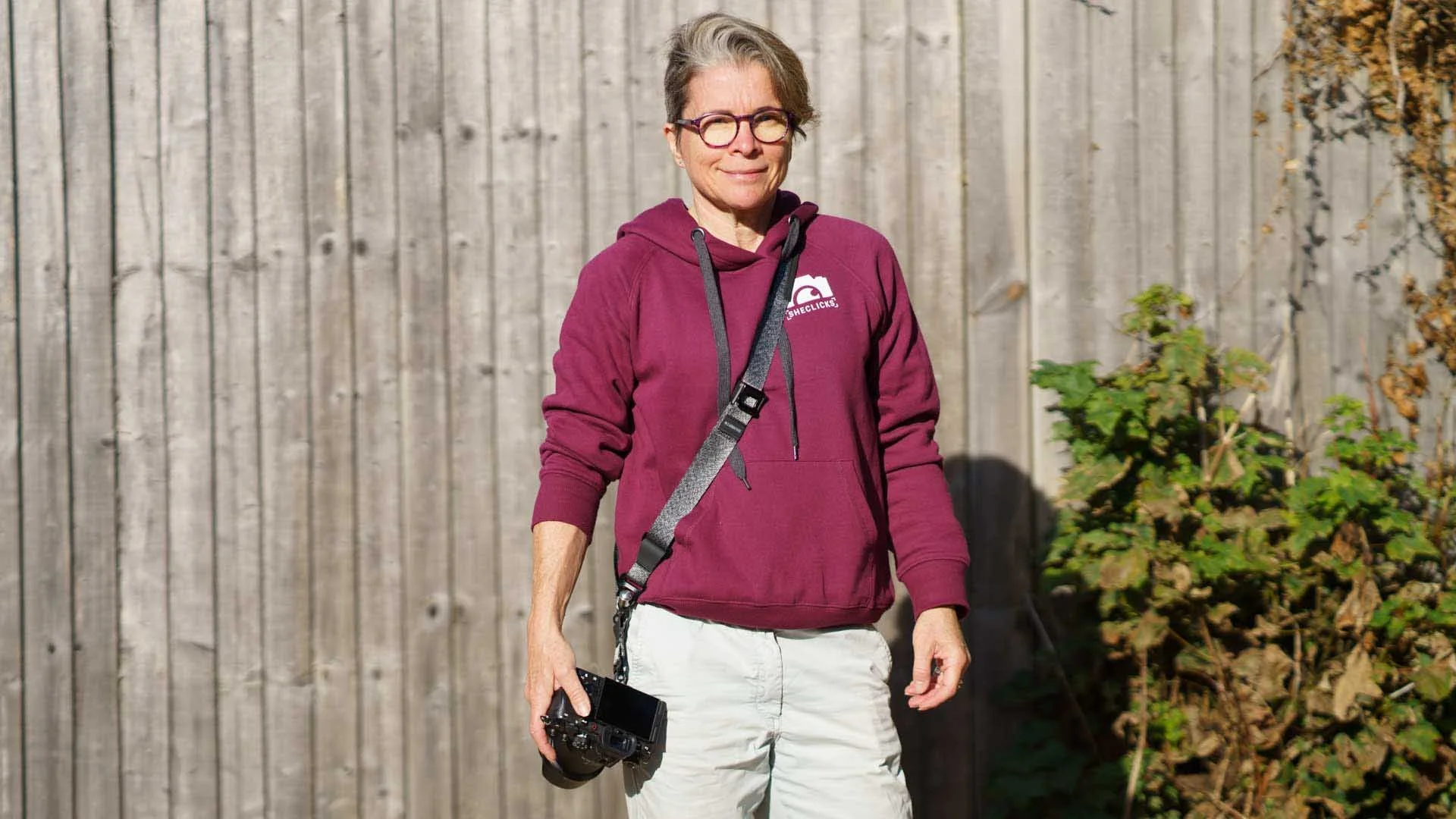Angela Nicholson in a maroon SheClicks hoodie with the 3 Legged Thing Axis 34P strap across her body