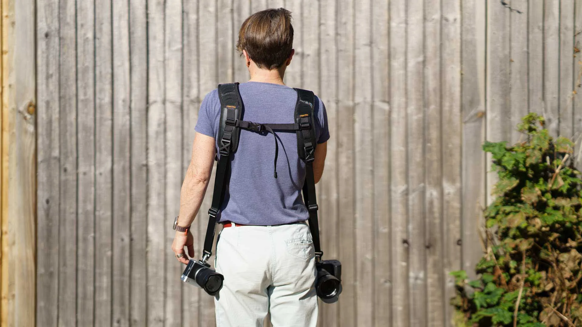 Angela Nicholson from behind while wearing the 3 Legged Thing Axis Twin Sling to carry two cameras