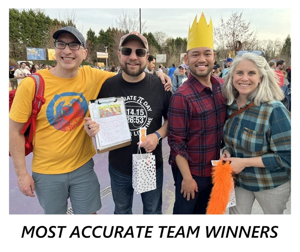 A group of four people, the most accurate winners, stand holding their clipboard. The centermost group member holds a polka dot gift bag.