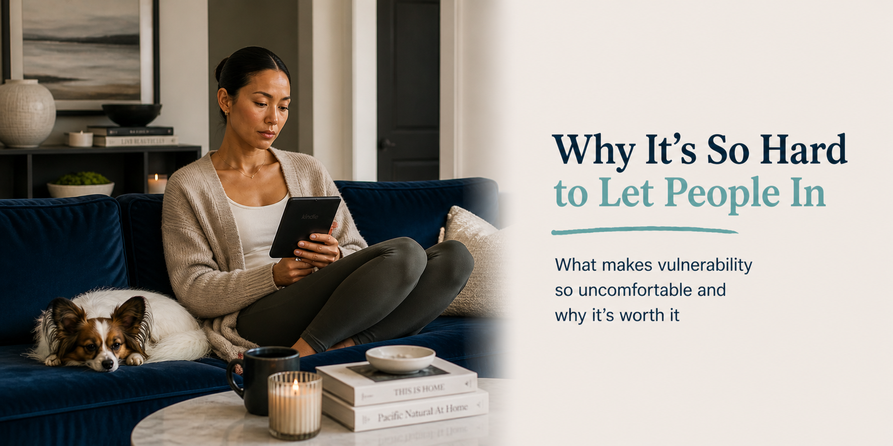 Woman sitting on a royal blue couch reading a Kindle in a calm, organized living room with a small dog nearby, representing loneliness and difficulty with vulnerability