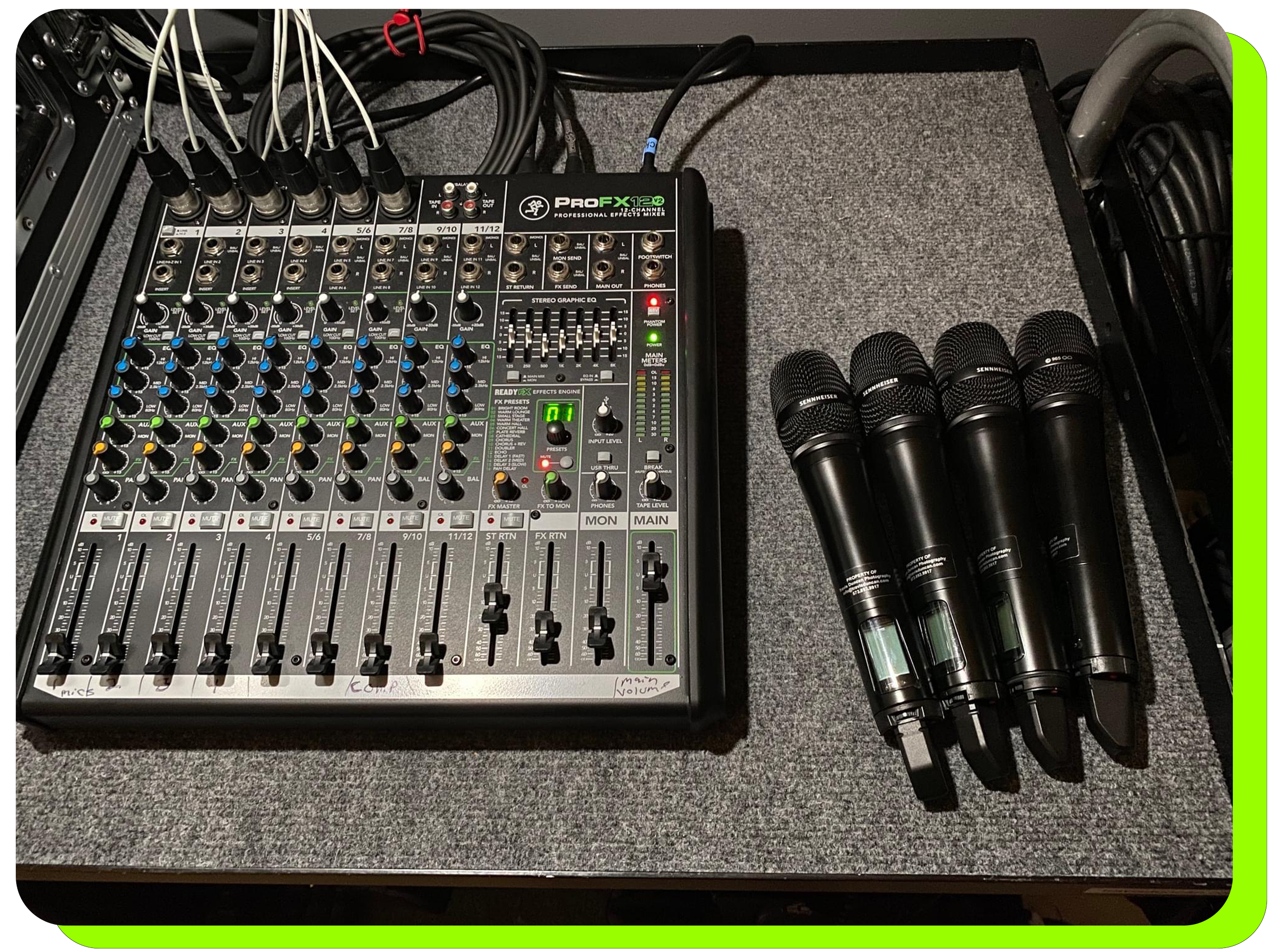 Professional audio mixing board sitting on a table top next to four professional quality Sennheiser microphones