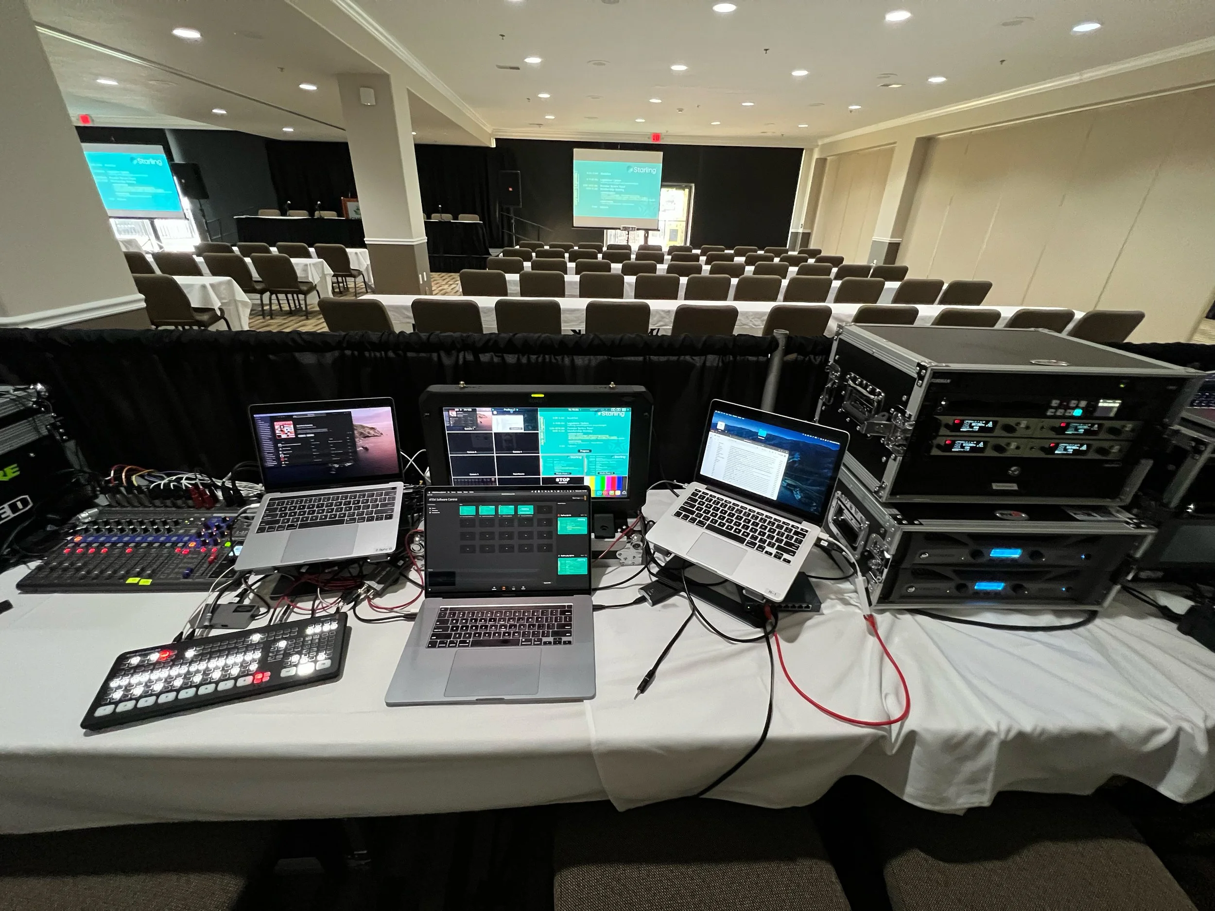 View from behind the AV tech table looking into a breakout room setup with two small projection screens in a classroom style room setup in Missouri
