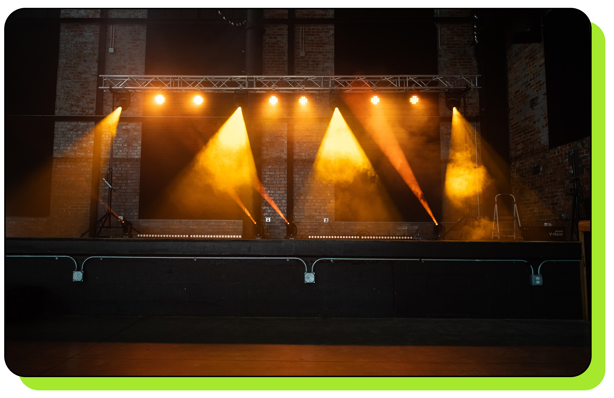 Intelligent lighting fixtures on stage showing amber colored beams onto empty stage