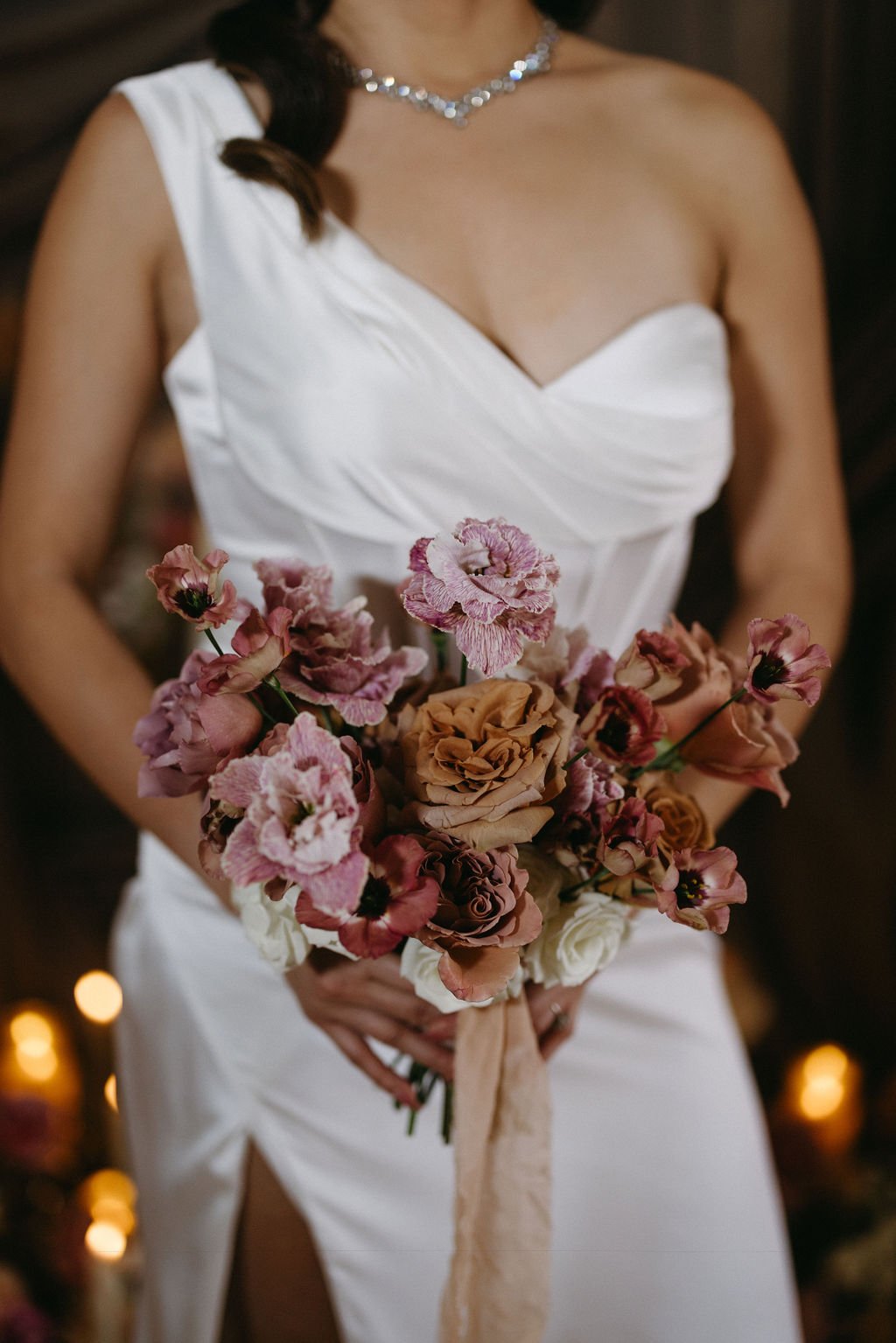 Close-up of a bride holding an vintage wedding bouquet featuring dusty mauve, mauve, and plum florals.
