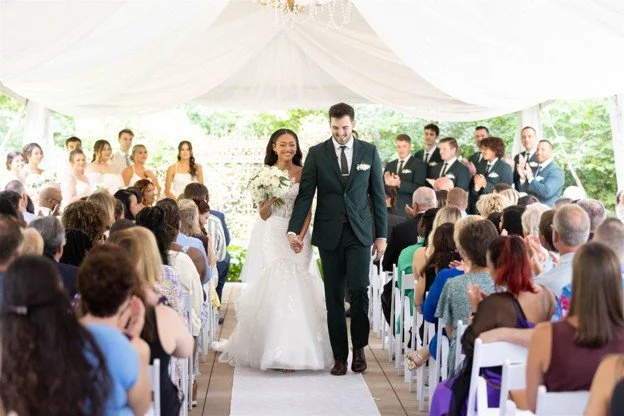 Elegant sailcloth tent reception setup with string lights and greenery for an outdoor weddin