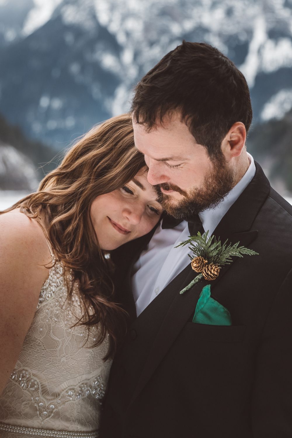 bride-snuggling-groom-snowy-mountains