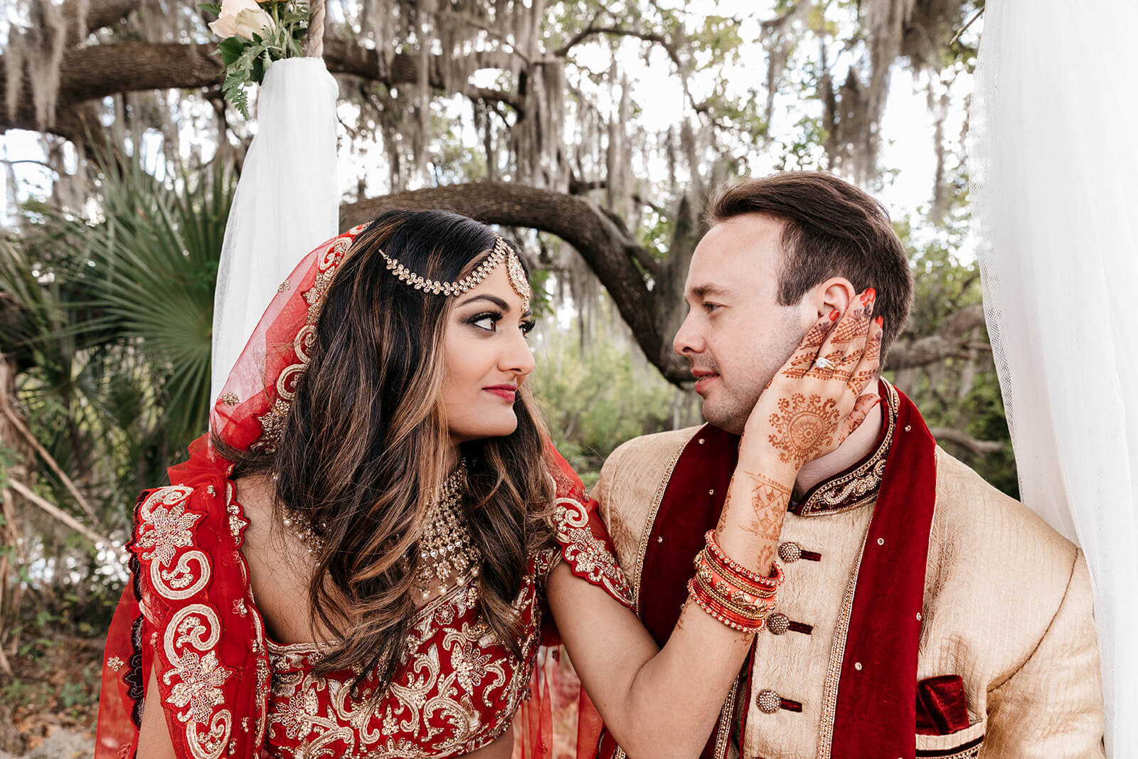  Bride holds grooms face in her mehndi covered hands 