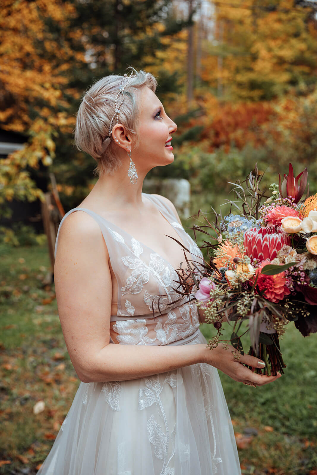  Bride with colorful bouquet checks out the autumn colors surrounds her cabin in the woods in Vermont 