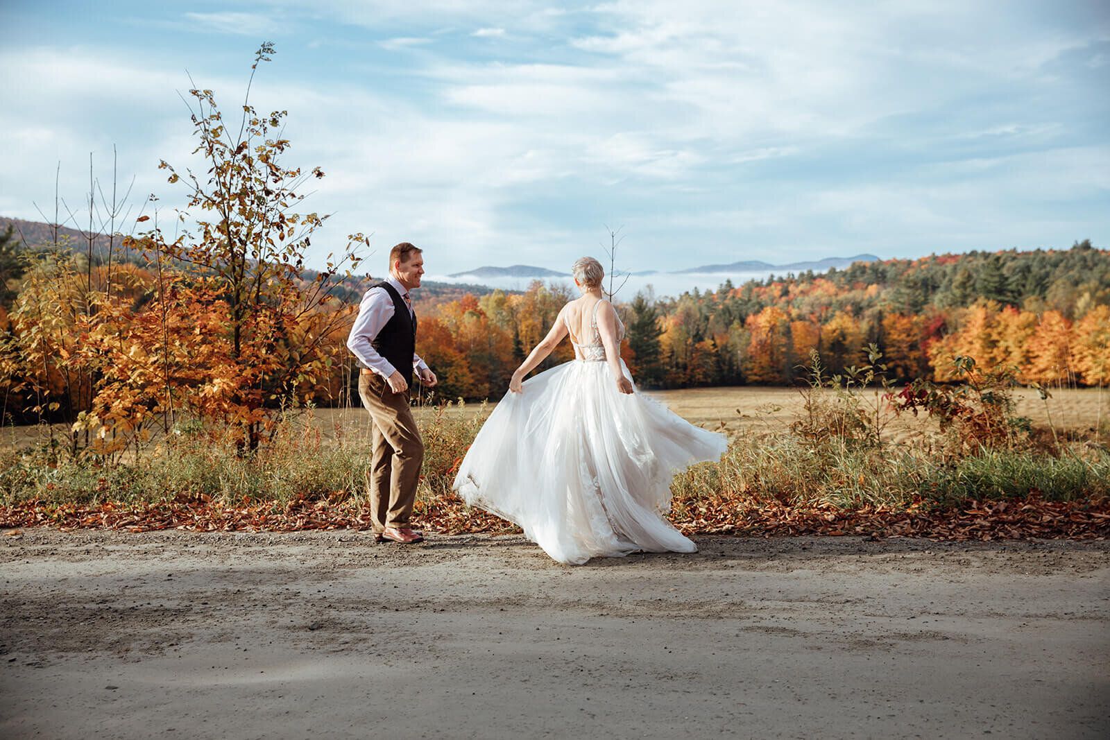  Bride and groom dance down a dirt road on their way to eloping in the early morning fog in Vermont 