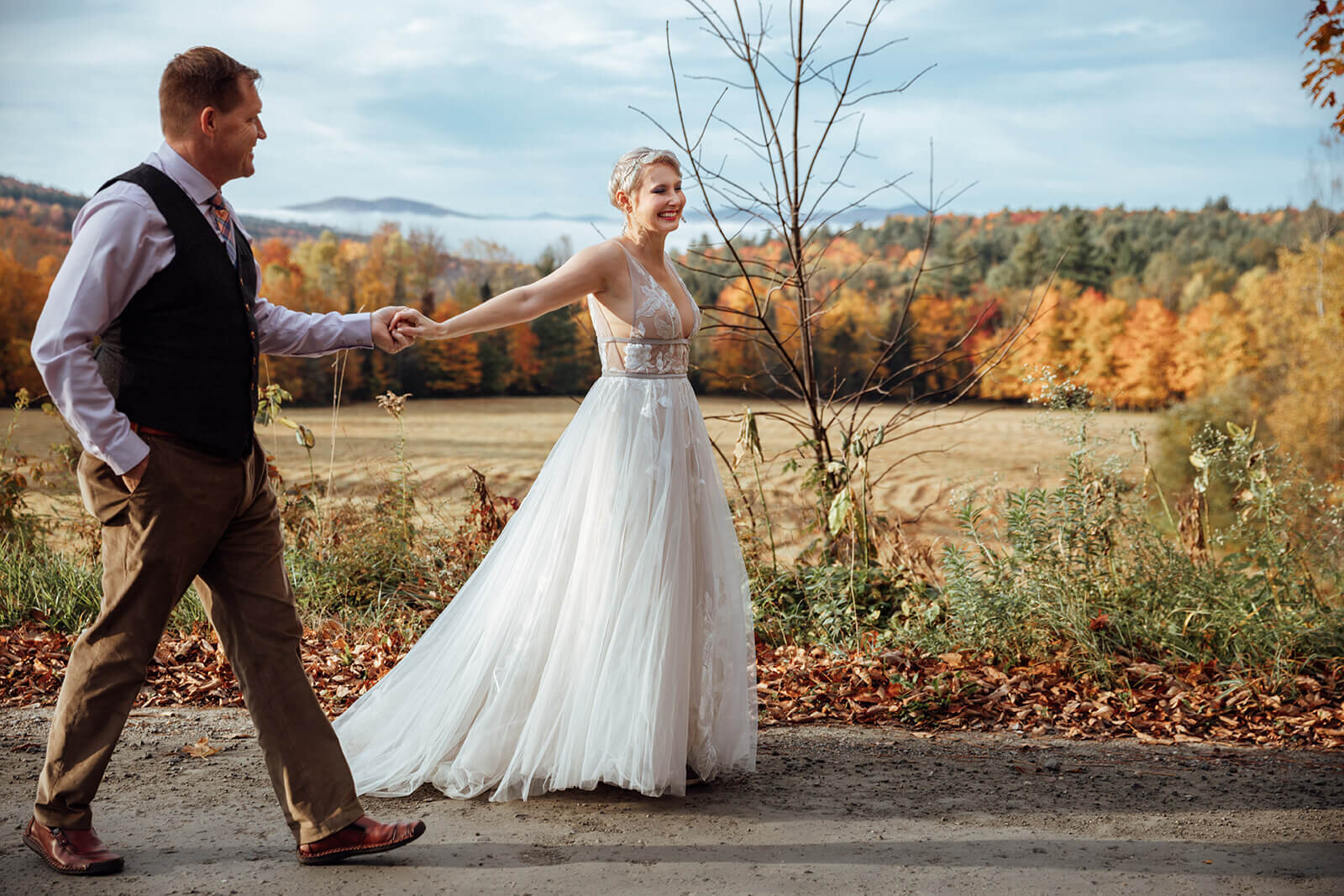  Bride and groom dance down a dirt road on their way to eloping in the early morning fog in Vermont 