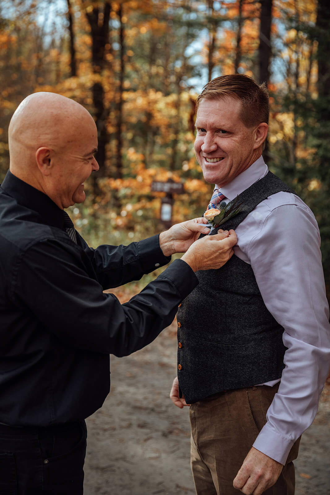  Officiant pins on the groom’s boutonnière as the couple prepares to hike to their elopement ceremony location  