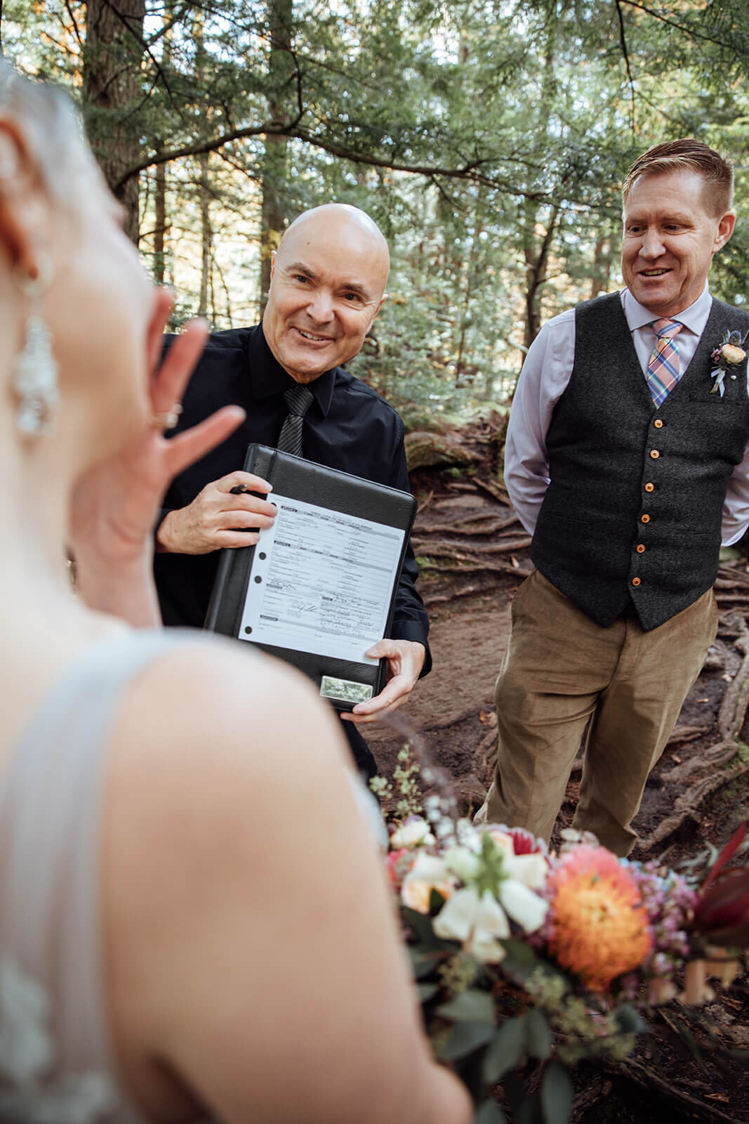  The officiant shows the couple their marriage certificate after their elopement at Warren Falls in Vermont 