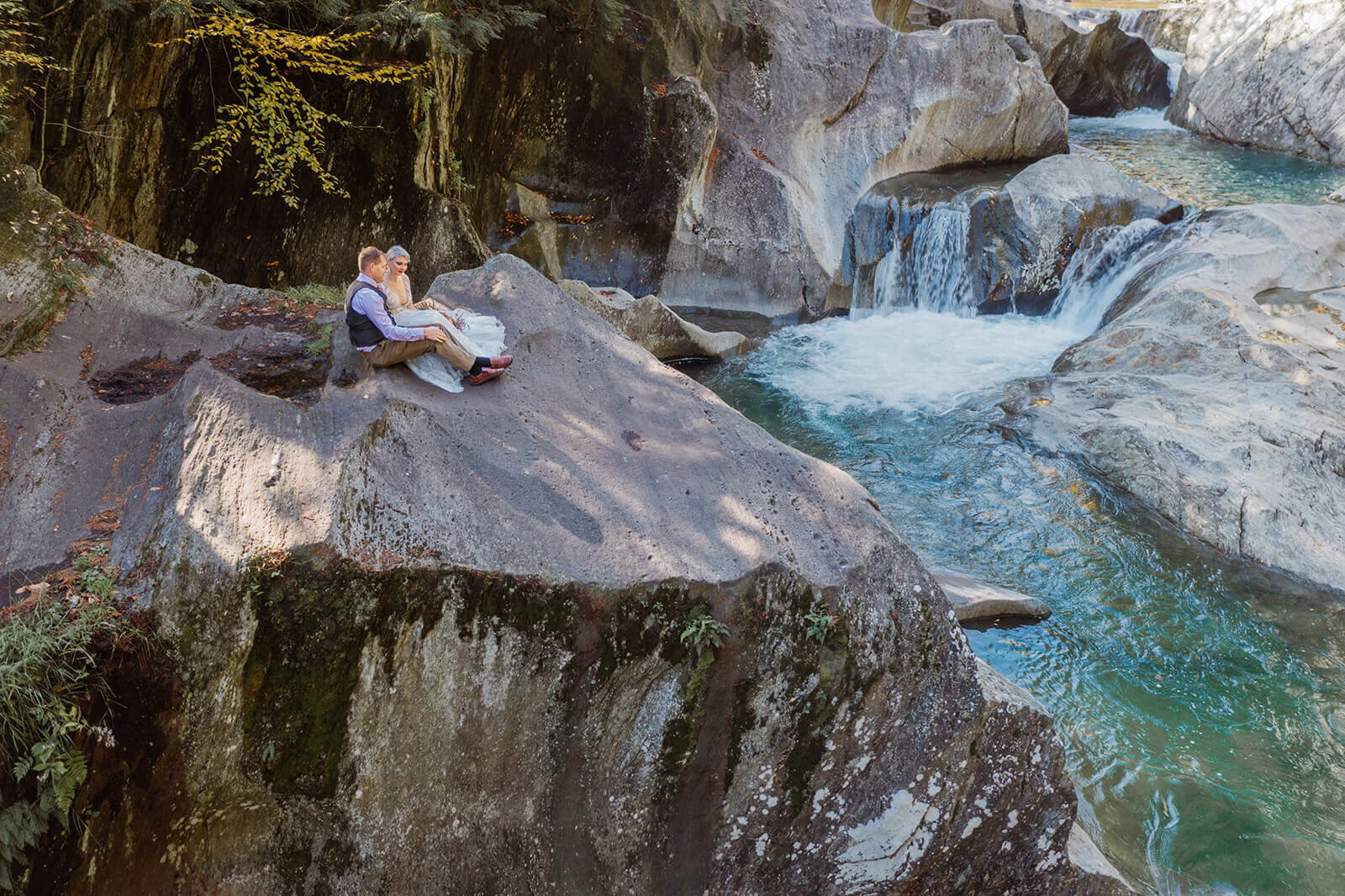  Bride and groom sit on cliff at Warren Falls after eloping. 