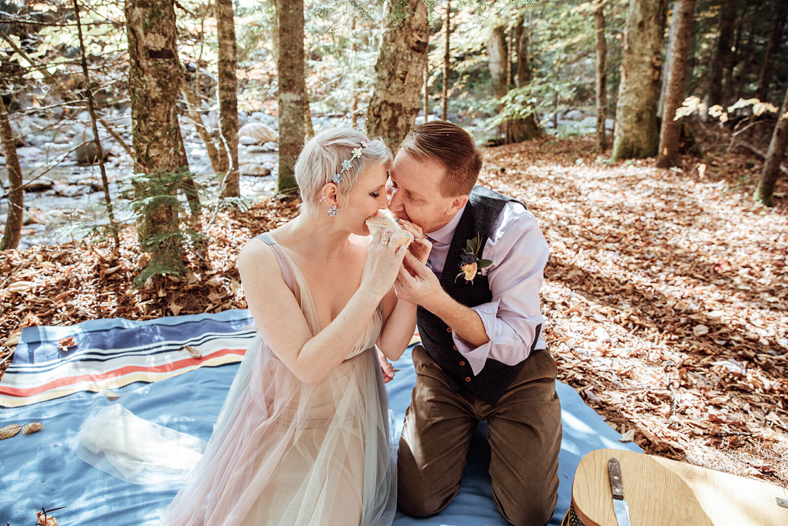  Bride and groom take a bite of the cake at their picnic after a Vermont elopement 